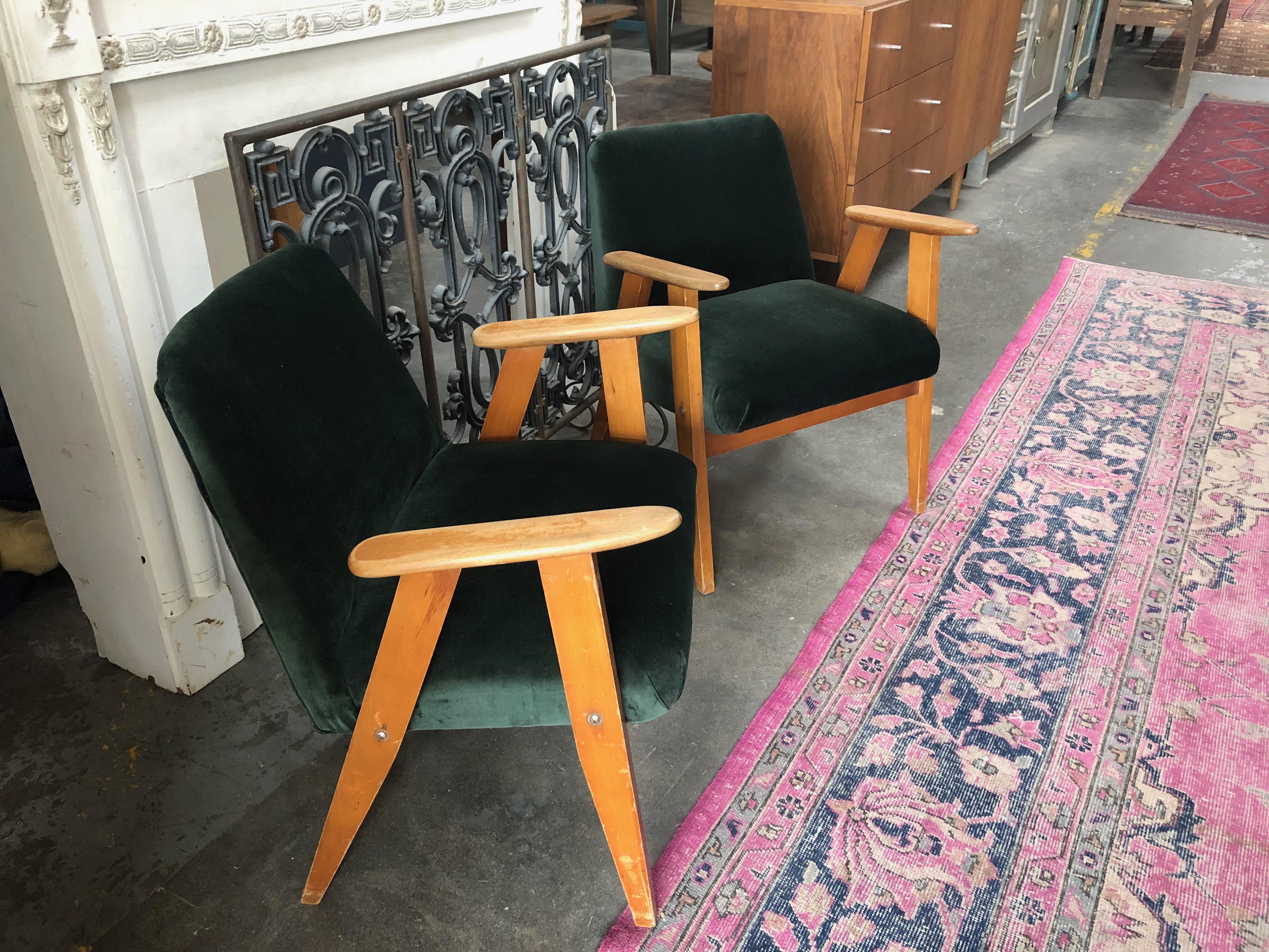 An elegant pair of reupholstered green velvet midcentury occasional chairs featuring a wooden frame and rounded arm rests. 

Dimensions: 27