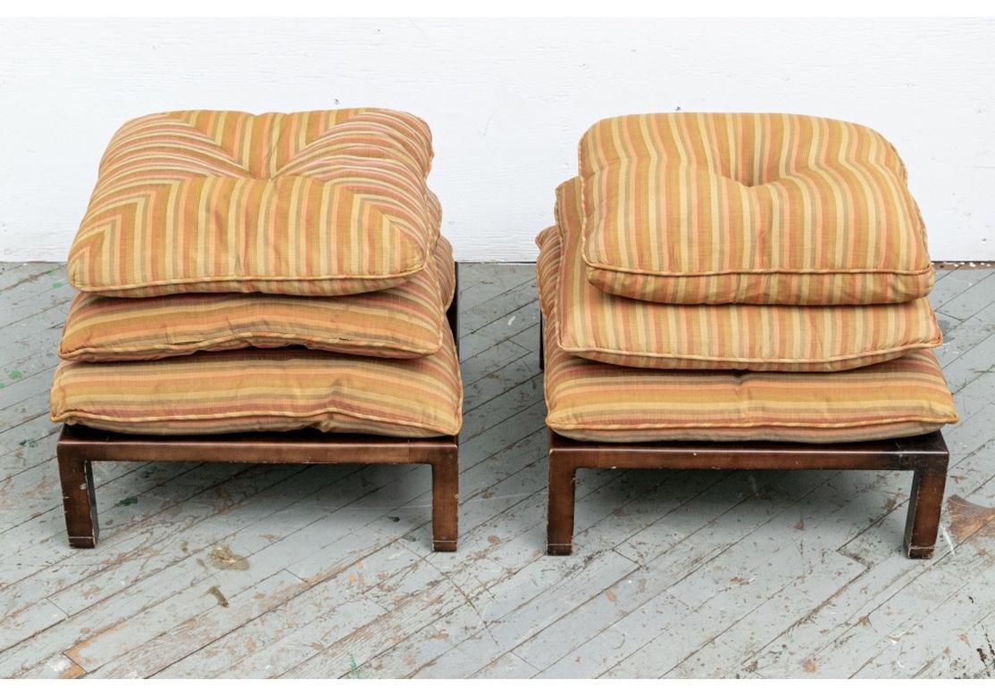 Ca. 1960. Square ottoman pair in a dark brown stain with square legs reminiscent of the type of furniture designed by Edward Wormley and produced by Dunbar from roughly the same Era. The tops with a tier of three separate cushions with center