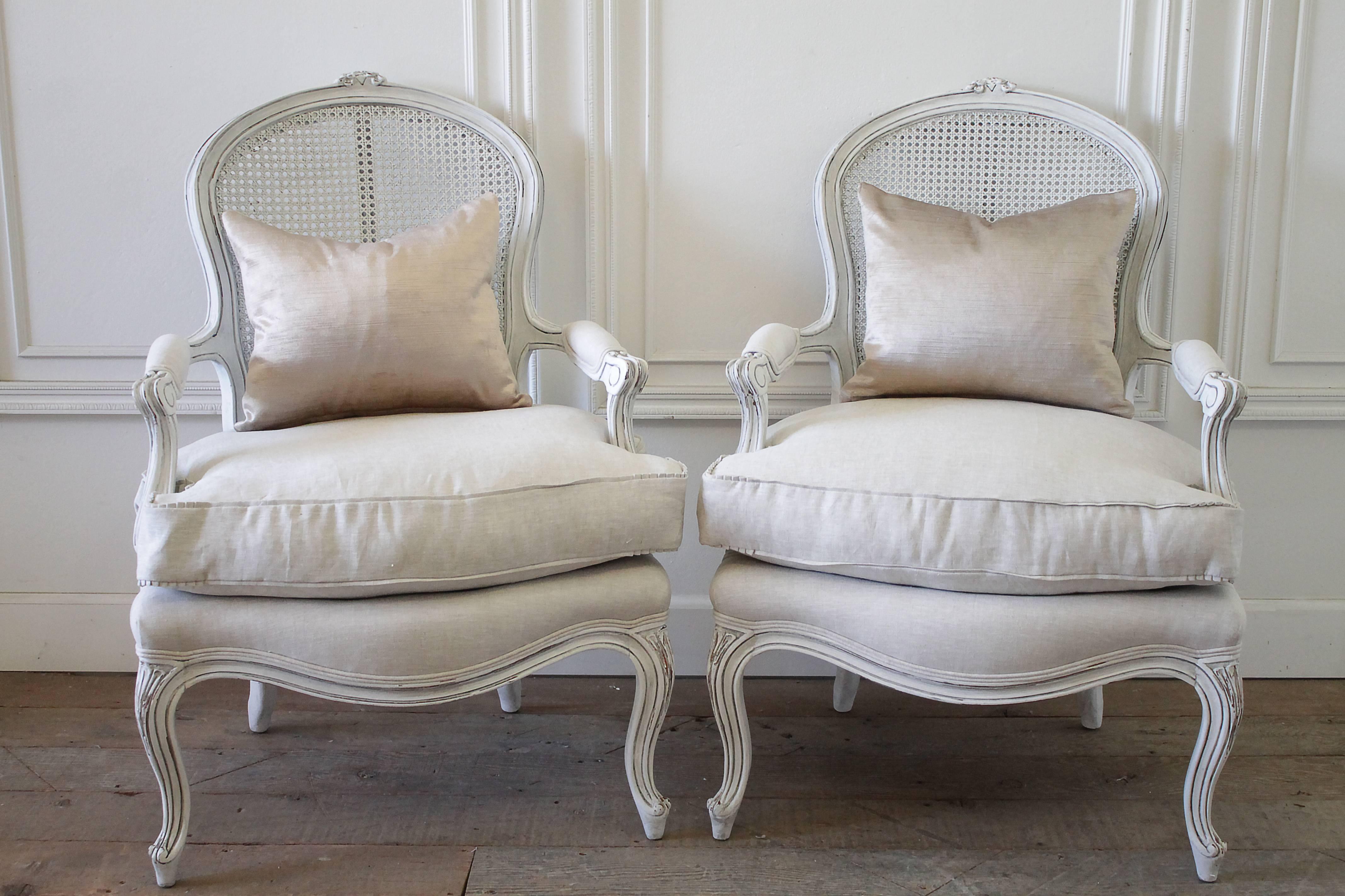 Pair of midcentury painted cane French style chairs
Painted in an oyster white finish, with subtle areas of distressing and hand applied antique glaze.
New upholstery in organic natural Belgian linen, with pleated ruffle slip covered cushions. New