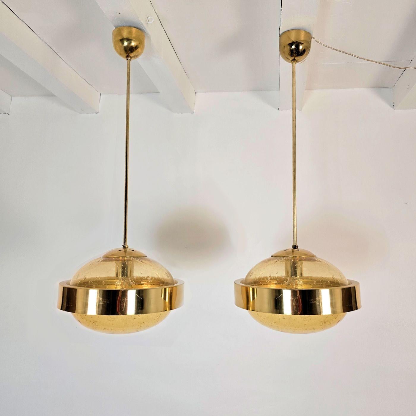 Paire de lampes suspendues modernes du milieu du siècle, Italie, années 1970.
Les lustres sont composés de montures en laiton poli et de 2 verres de Murano soufflés à la main.
Le verre de Murano est d'une couleur ambrée chaude, avec des bulles d'air