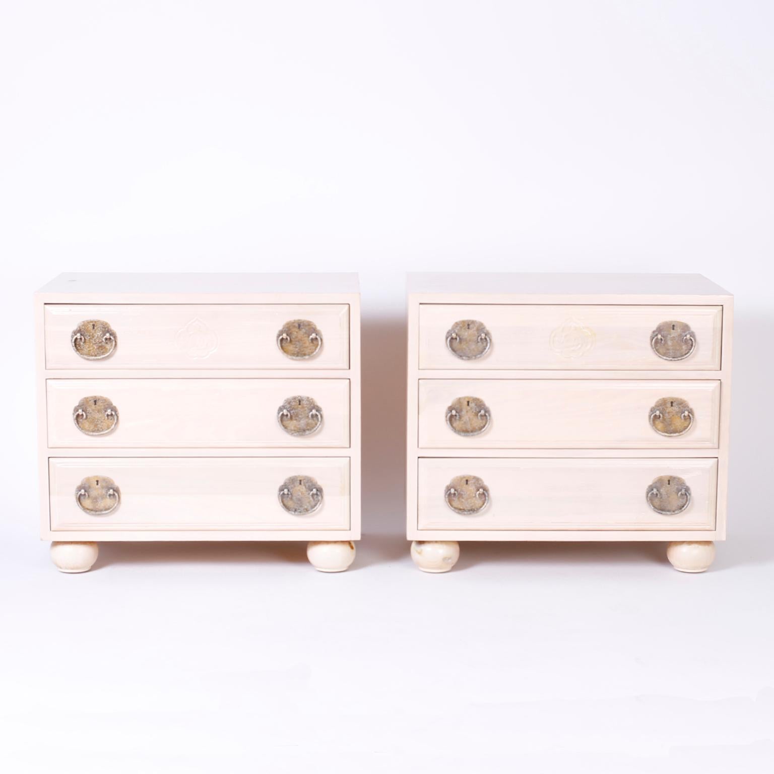 Vogue pair of midcentury three-drawer night stands or chests with an unusual pickled pine finish, sleek Asian Modern form, speckled brass Ming style hardware, and proper bun feet.