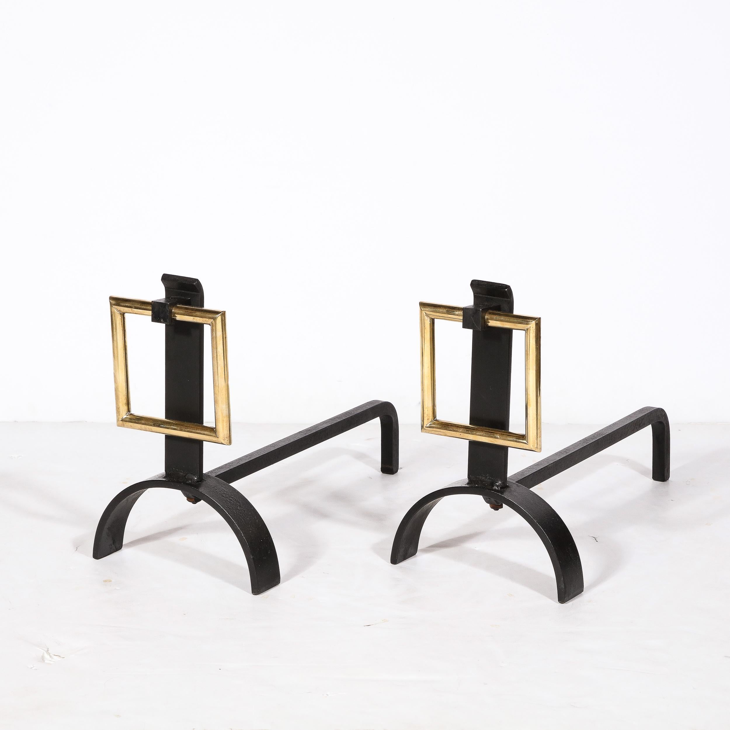 This dynamic yet reserved Pair of Mid-Century Modernist Buckle Form Andirons in Polished Brass & Black Enamel are by the esteemed designer Donald Deskey, originating from the United States, Circa 1950. Sleek and flawlessly executed, they feature a