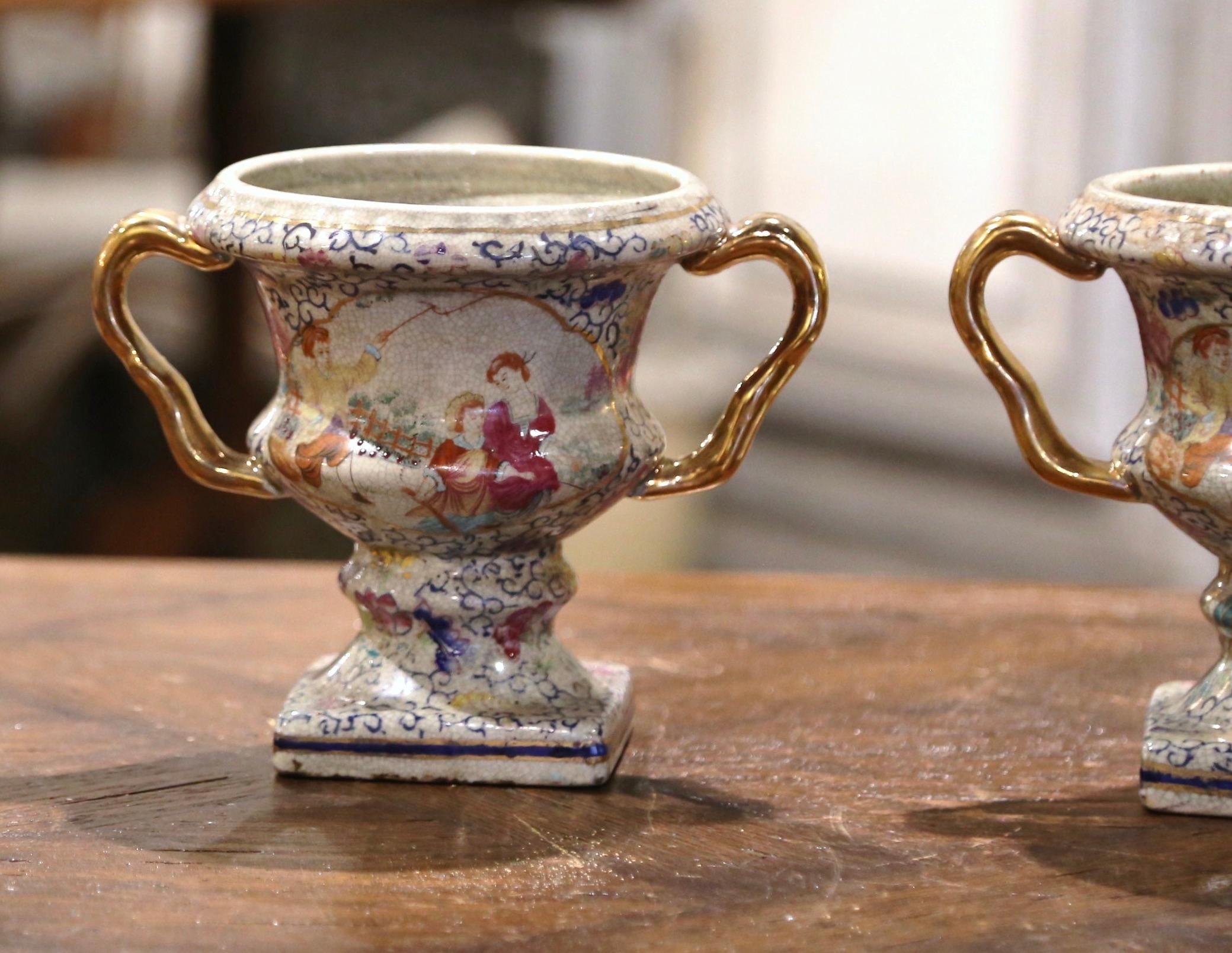 Dekorieren Sie einen Kaminsims mit diesem farbenfrohen Paar chinesischer Porzellanvasen; hergestellt in China, um 1970. Die urnenförmigen Vasen sind mit floralen Motiven und Mustern verziert. Sie sind außerdem mit vergoldeten Griffen verziert. Die