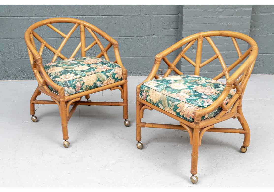 Pair of Midcentury lounge chairs with open fretwork design in the manner and style of Henry Link & McGuire. The legs are conjoined by X-form stretchers and terminated with brass casters. 
The chairs come with fixed floral upholstered seats and