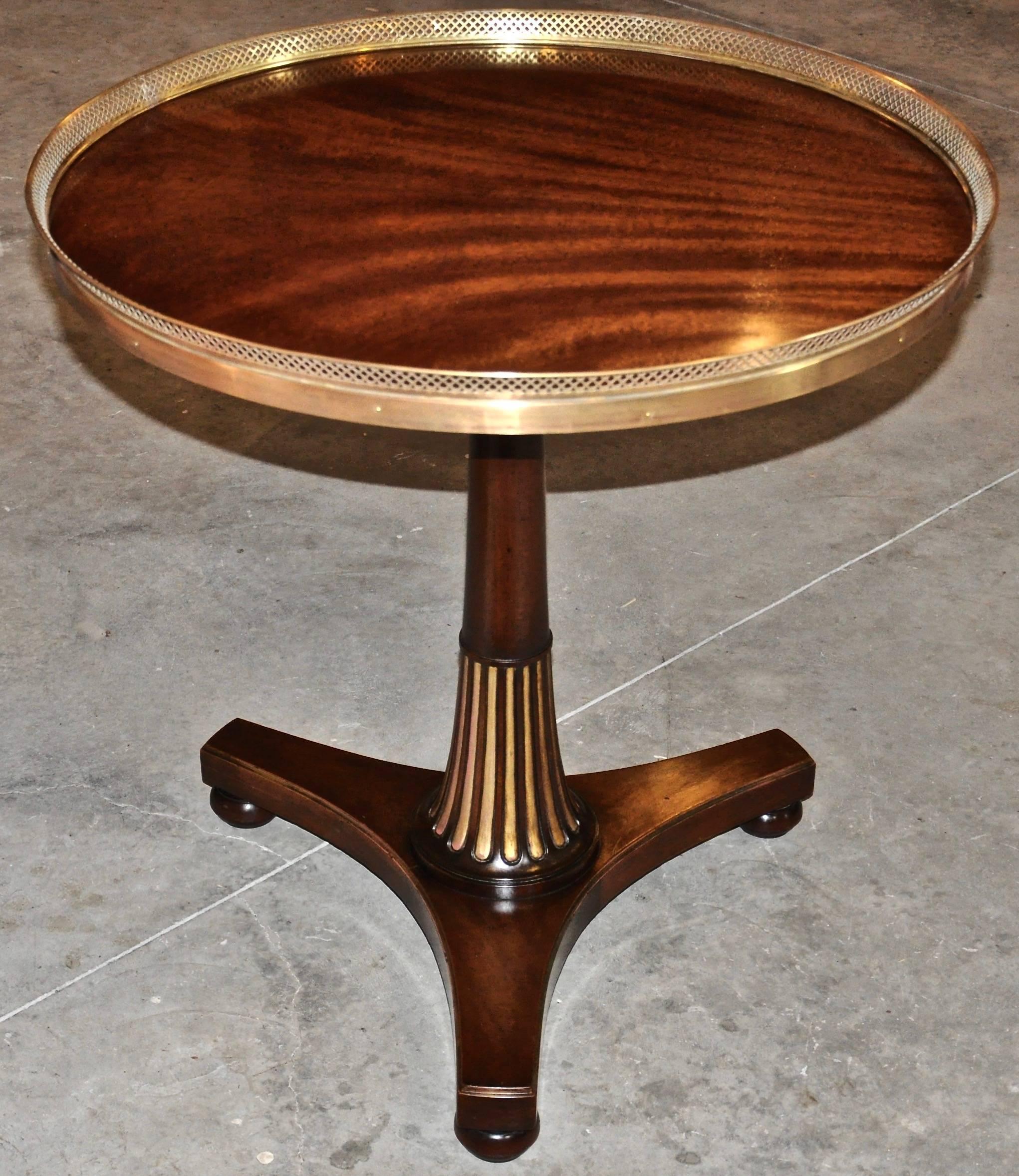 Pair of midcentury side tables in Regency style.

Well figured mahogany with tripartite base, gilded Egyptian fluting and brass gallery. Quite stylish pair of gueridons in manner of Marsh and Tatham.