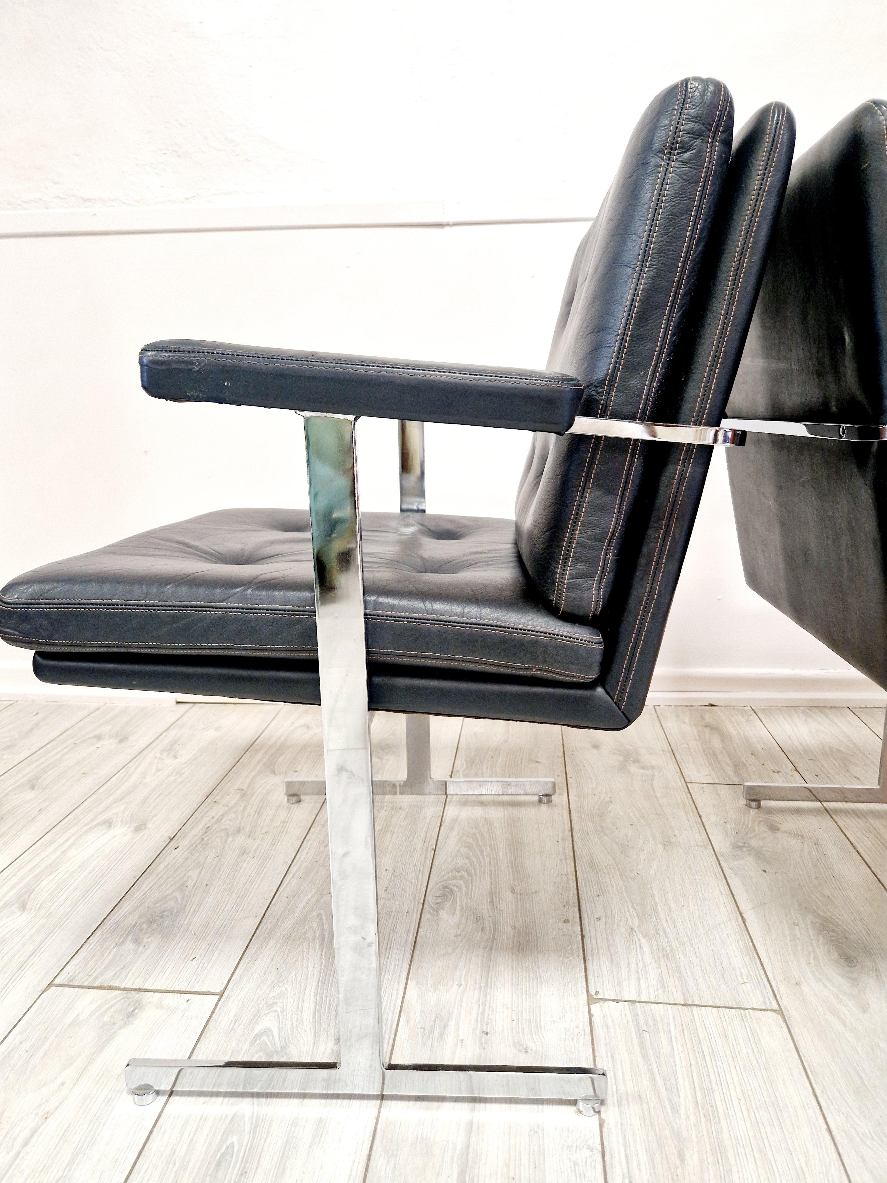 Realizzata con un design senza tempo, questa coppia di sedie lounge Robin Day Hille Delphi emana la quintessenza dello stile Mid-Century Modern. L'elegante rivestimento in pelle nera e le finiture cromate lucide incarnano l'estetica dell'epoca,
