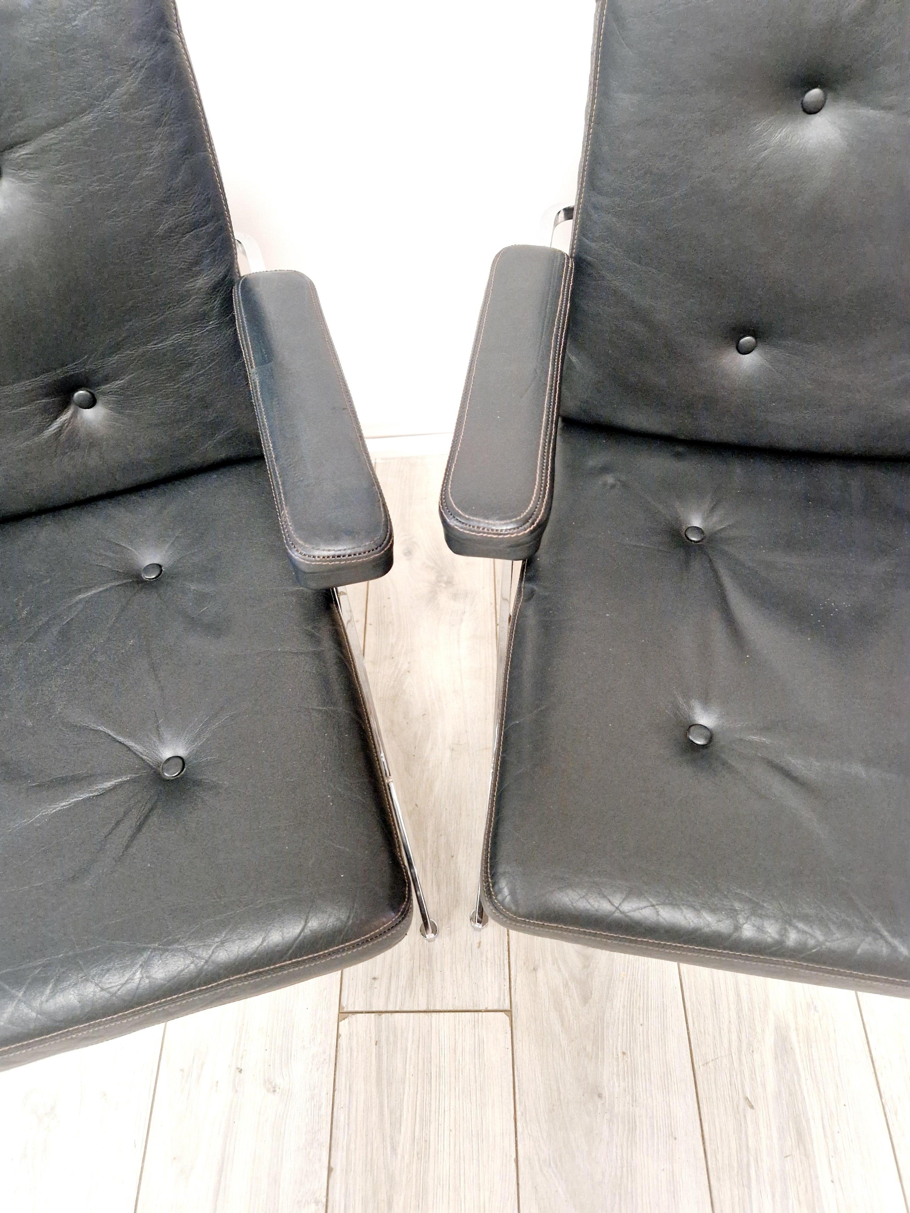 Fabricadas con un diseño atemporal, este par de tumbonas Robin Day Hille Delphi rezuman el estilo moderno de mediados de siglo por excelencia. La elegante tapicería de cuero negro y el acabado cromado brillante encapsulan la estética de la época,