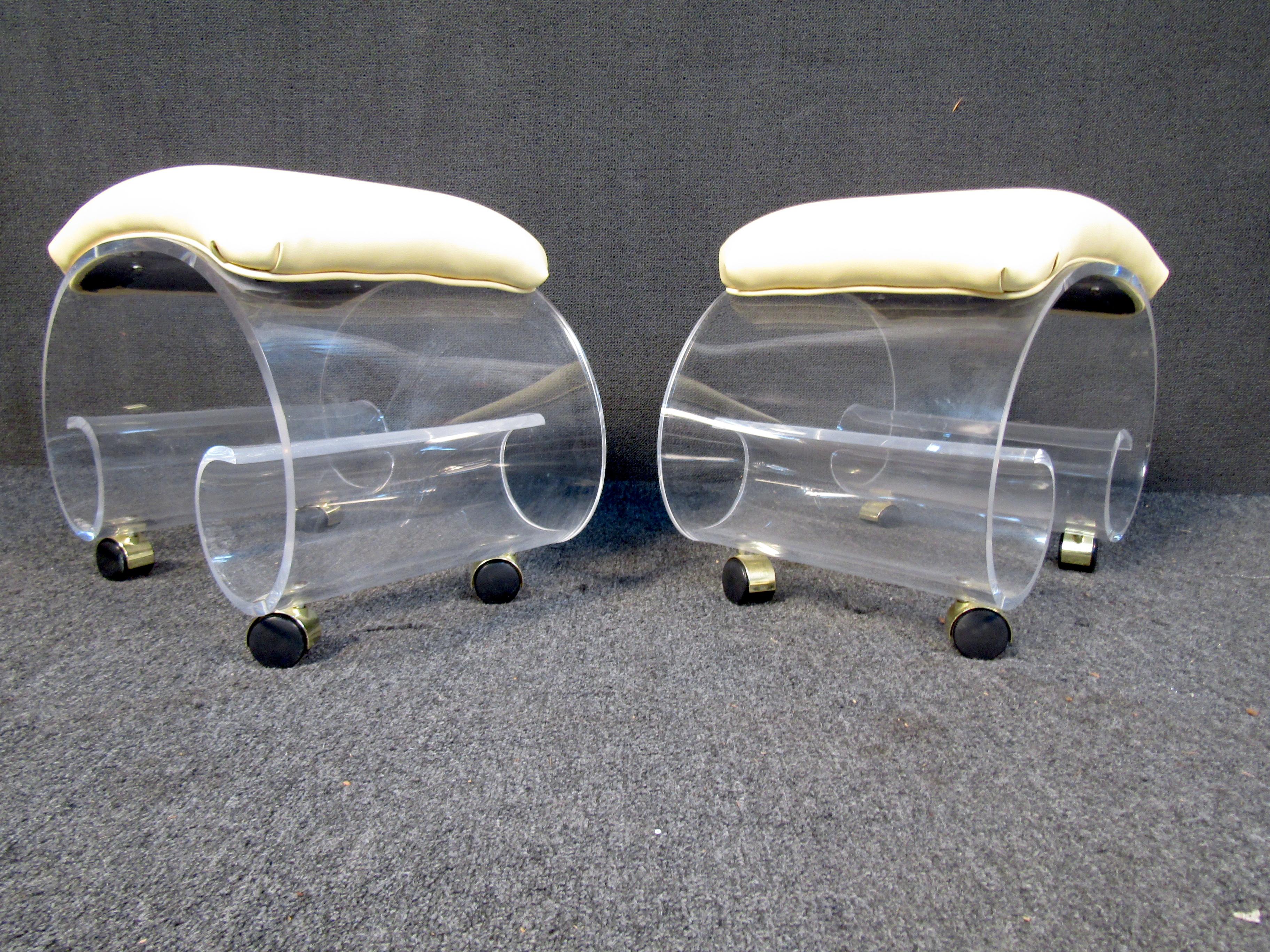 Pair of Lucite vanity stools featuring a spiral bottom sitting on four rolling wheels in a bronze finish. The top also has a square vinyl pad. Please confirm item location (NY or NJ.).