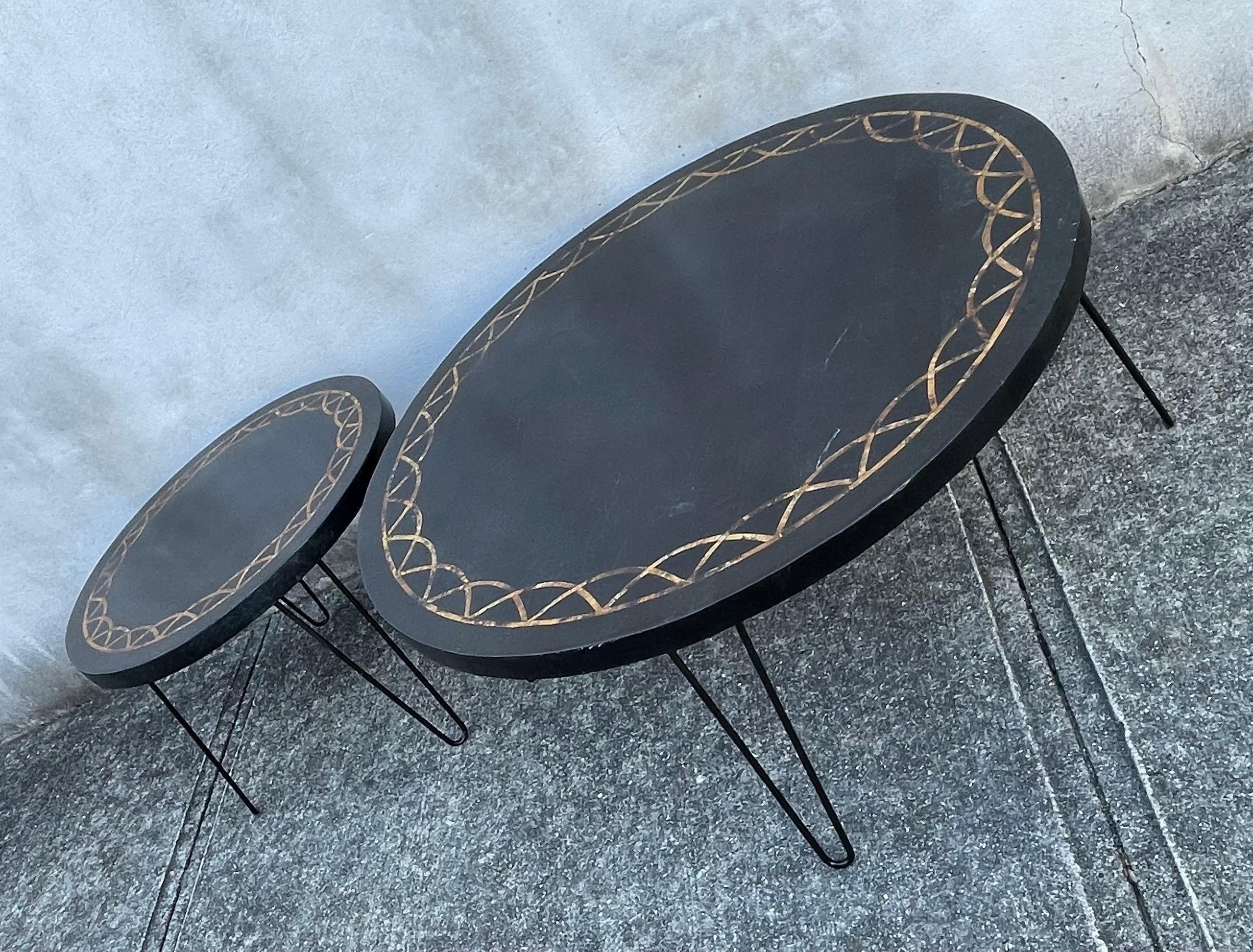 Pair of Mid-Century Modern round coffee tables with hairpin legs. Black faux tiles with gold mosaic inlay. Small table dimensions, 26 inches in diameter by 17.50 inches tall.