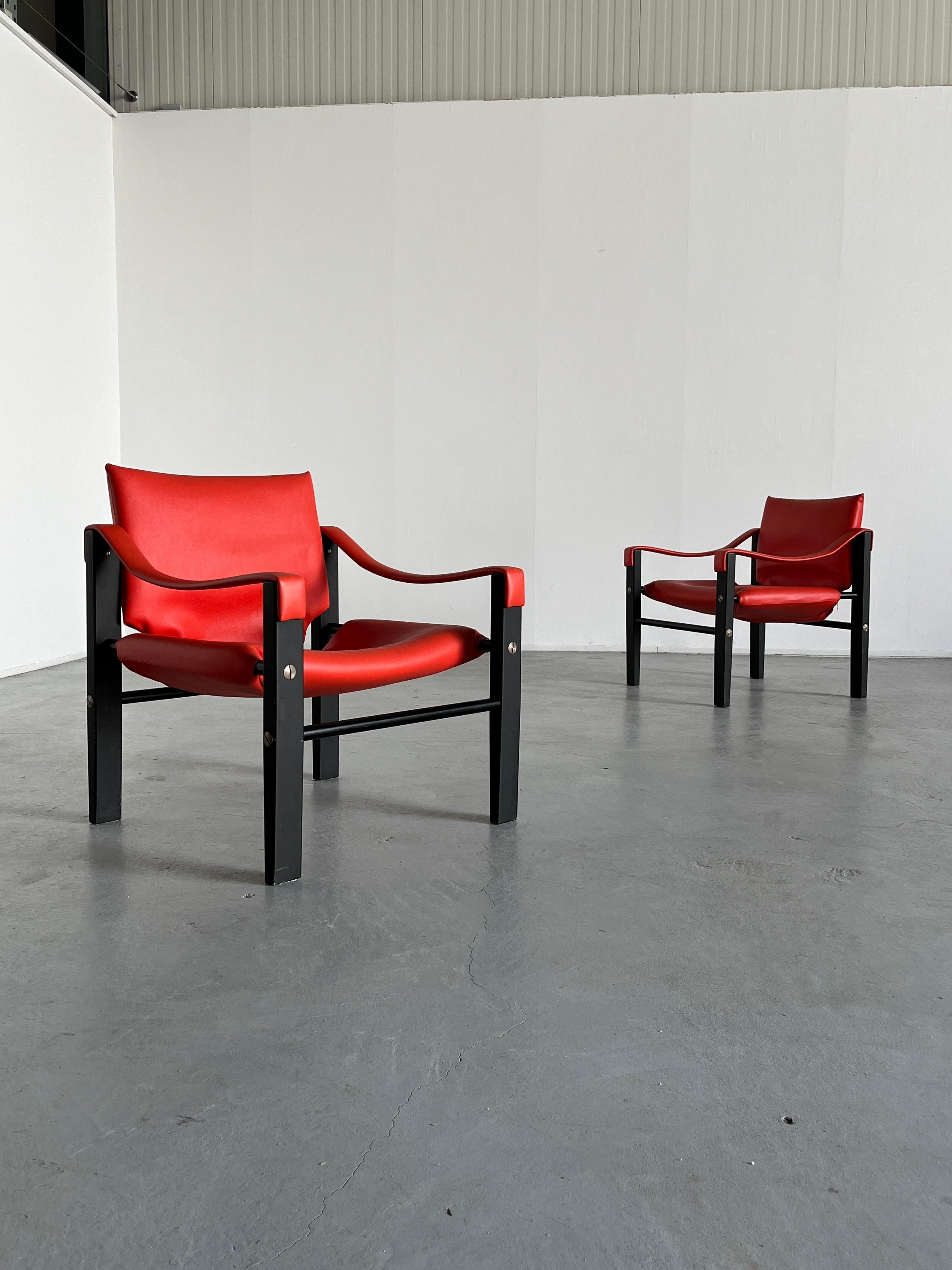 Rare edition vintage Safari chairs designed by Maurice Burke for Arkana Furniture, wearing their original red faux leather or vinyl with a coloured teak frame, tubular metal runners, and steel screw details. 1960s production, both original and