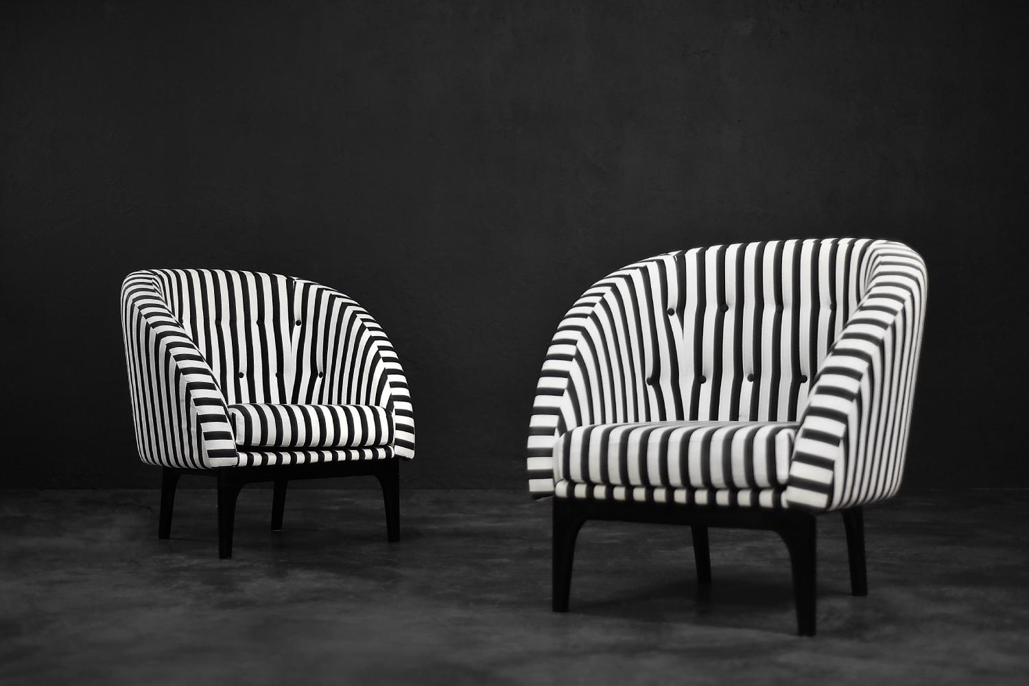 This set of two armchairs was made in Denmark during the 1960s. They are upholstered in a thick black and white striped fabric. Black and white is a classic, timeless color combination. In addition, the striped pattern due dynamics and brings