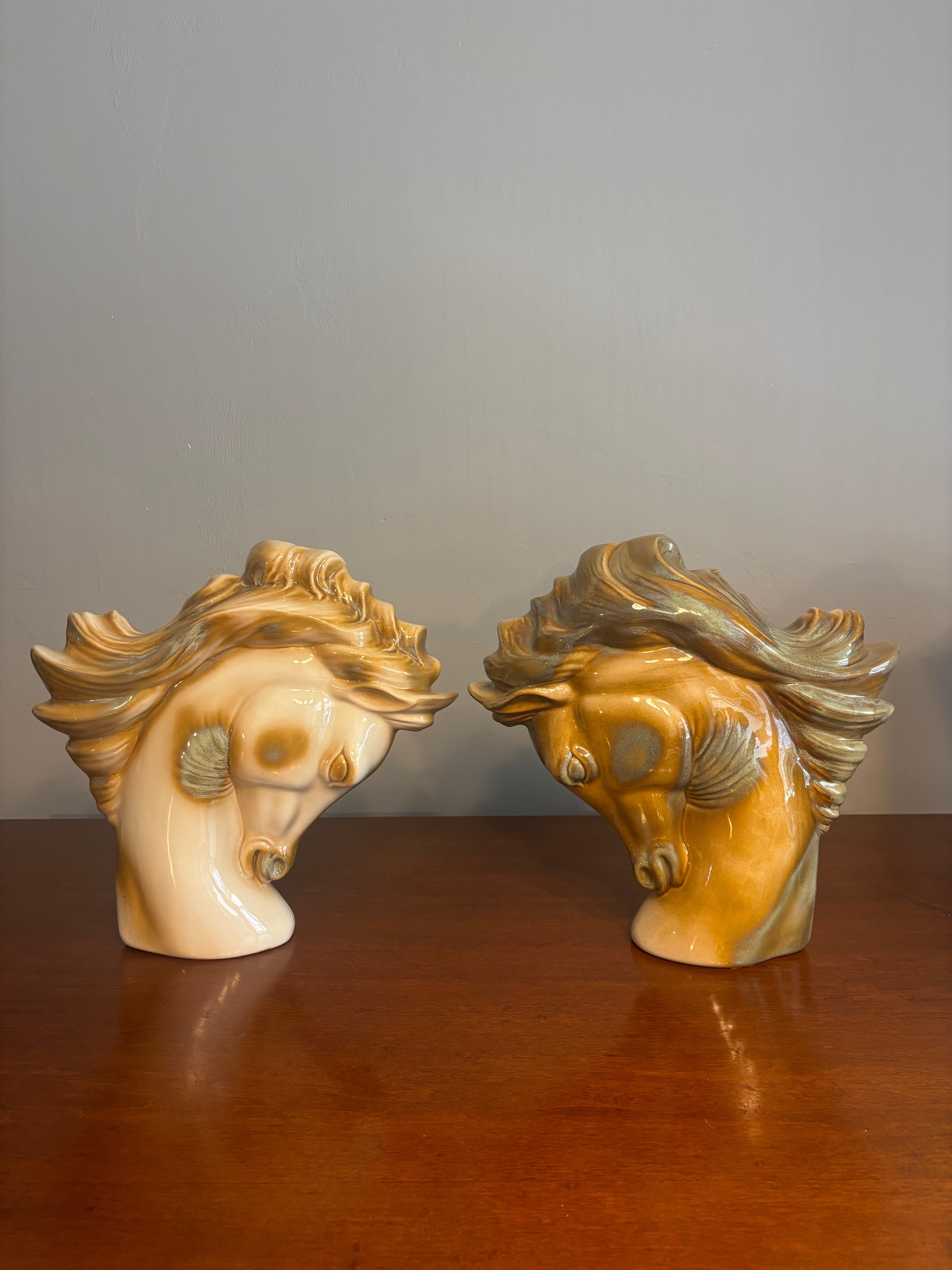 Una notevole coppia di sculture di teste di cavallo in ceramica della metà del secolo scorso che si distinguono per la loro forma espressiva e lo smalto luminoso. Ogni pezzo è alto 14 pollici e largo 13 pollici e cattura un momento di forza