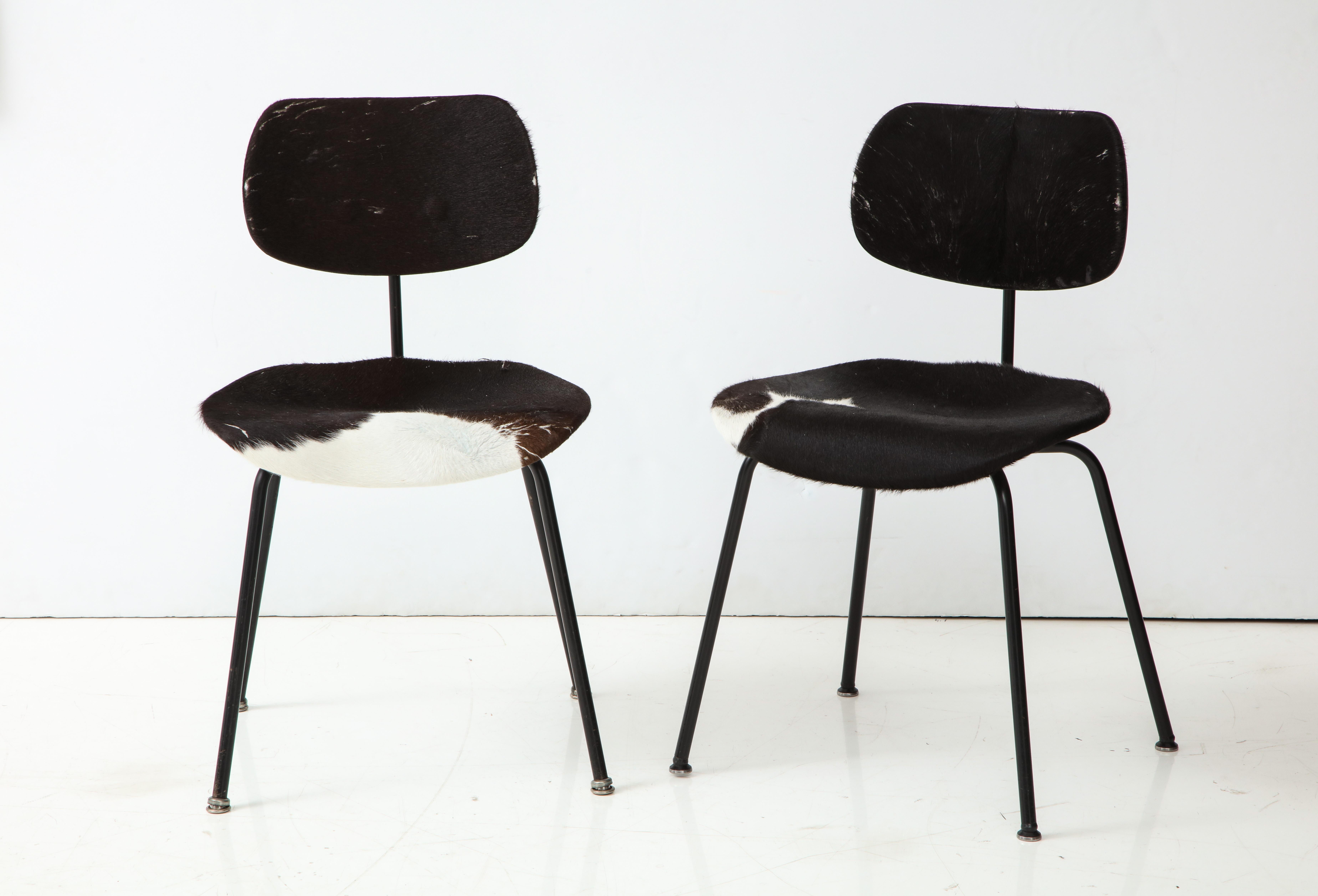 Classic pair of mid-century SE 68 chairs by German architect and designer Egon Eiermann. 

Clean, modernist design consists of a tubular metal frame, curved seat and backrest, as well as original black and white cowhide. Maker and distributor's