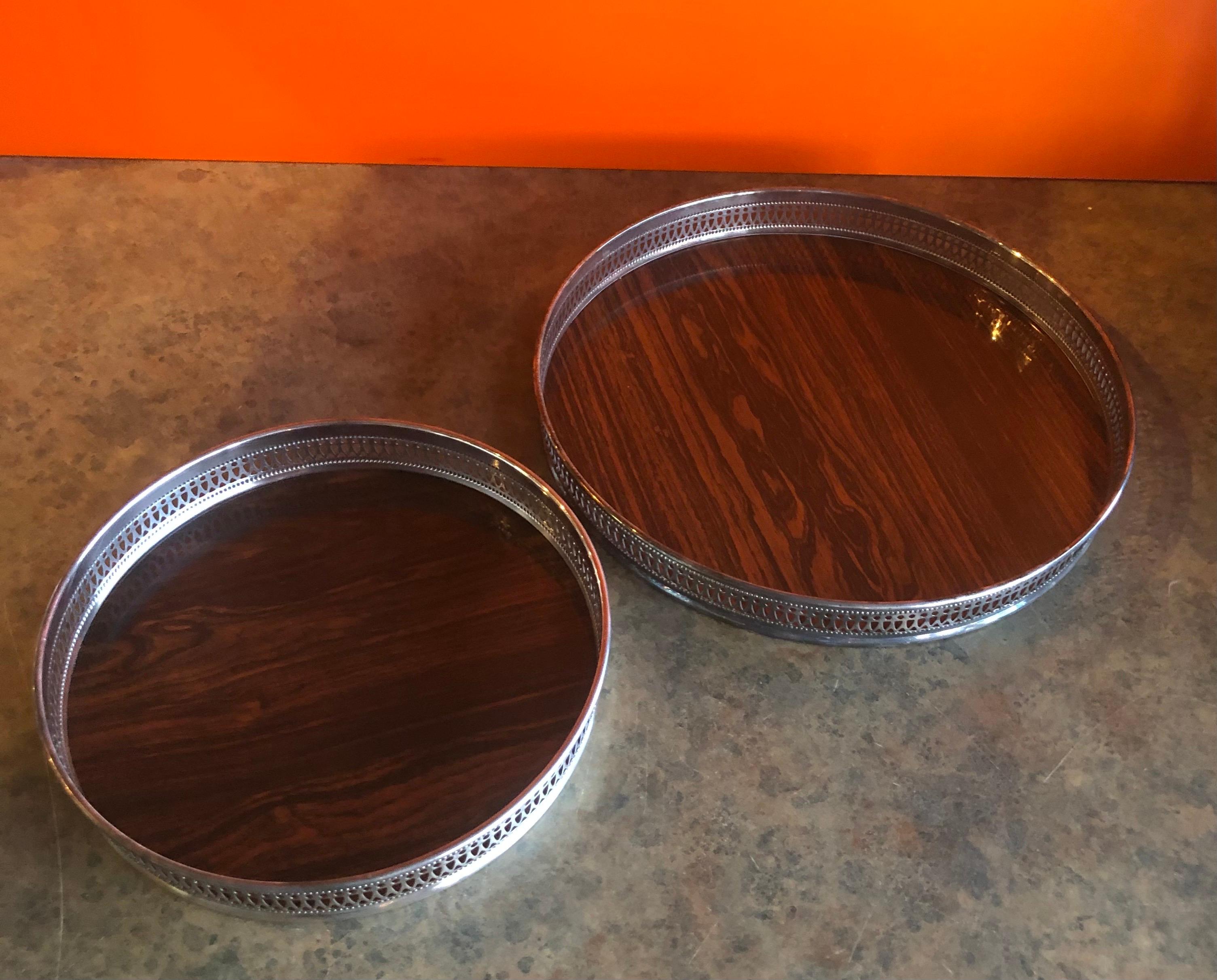Pair of midcentury rosewood Formica serving trays with silver plate edge by Sheffield Silver Co., circa 1970s. The trays are in very good vintage condition and would be an excellent match with a coffee or tea set. The larger one measures 12.25
