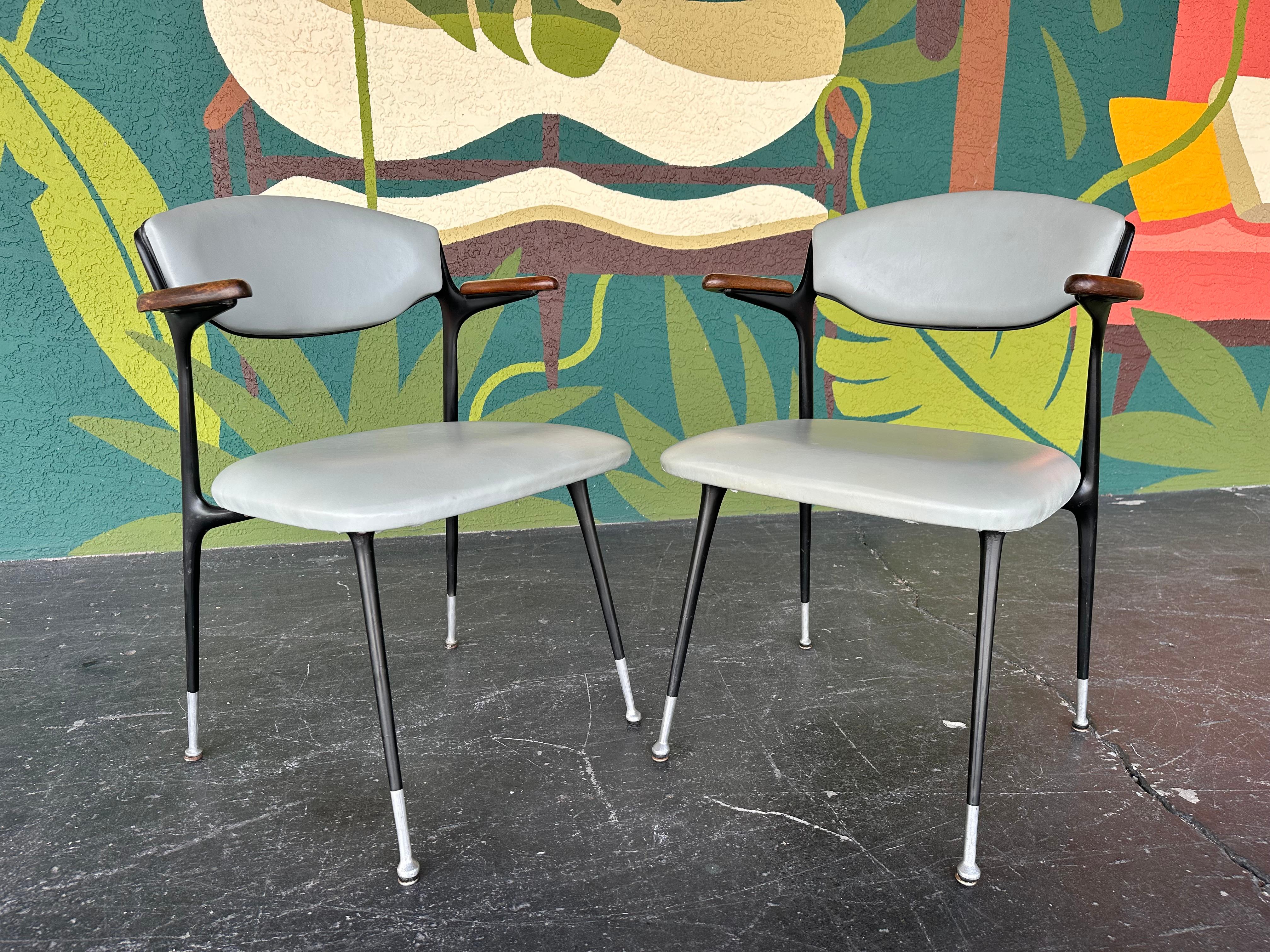 Pareja de sillones Gacela modernos de mediados de siglo atribuidos a Shelby Williams. Equipado con la tapicería original de vinilo azul claro con estructura de acero negro y reposabrazos de madera. Perfectas como sillas de invitados para tu