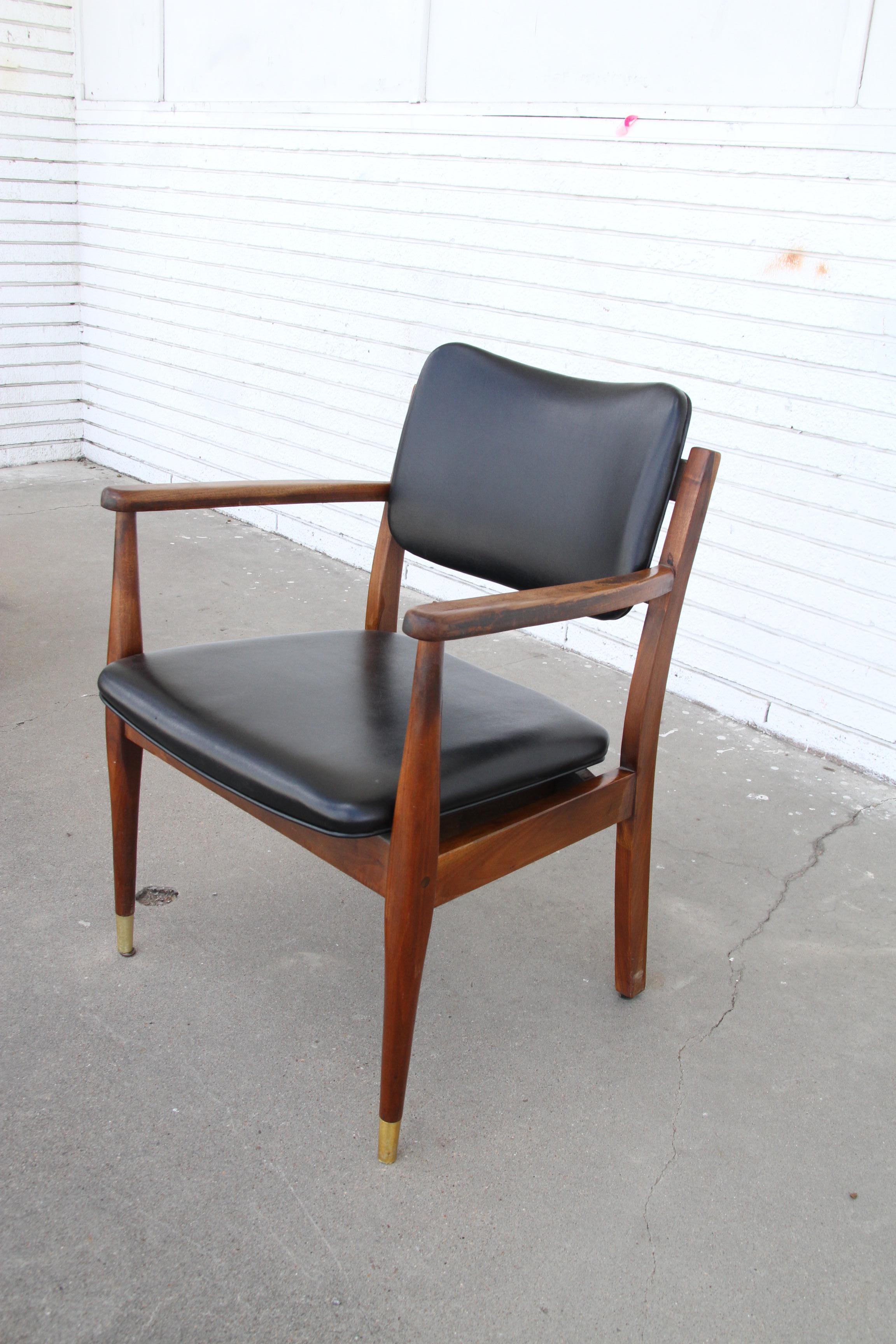 Pair of Mid Century Side Guest Chairs by Gregson

Mid century modern pair of arm chairs with walnut frames, tapered brass tipped legs, upholstered in black naugahyde, with a brass tack detail.  
Signed by Gregson Manufacturing