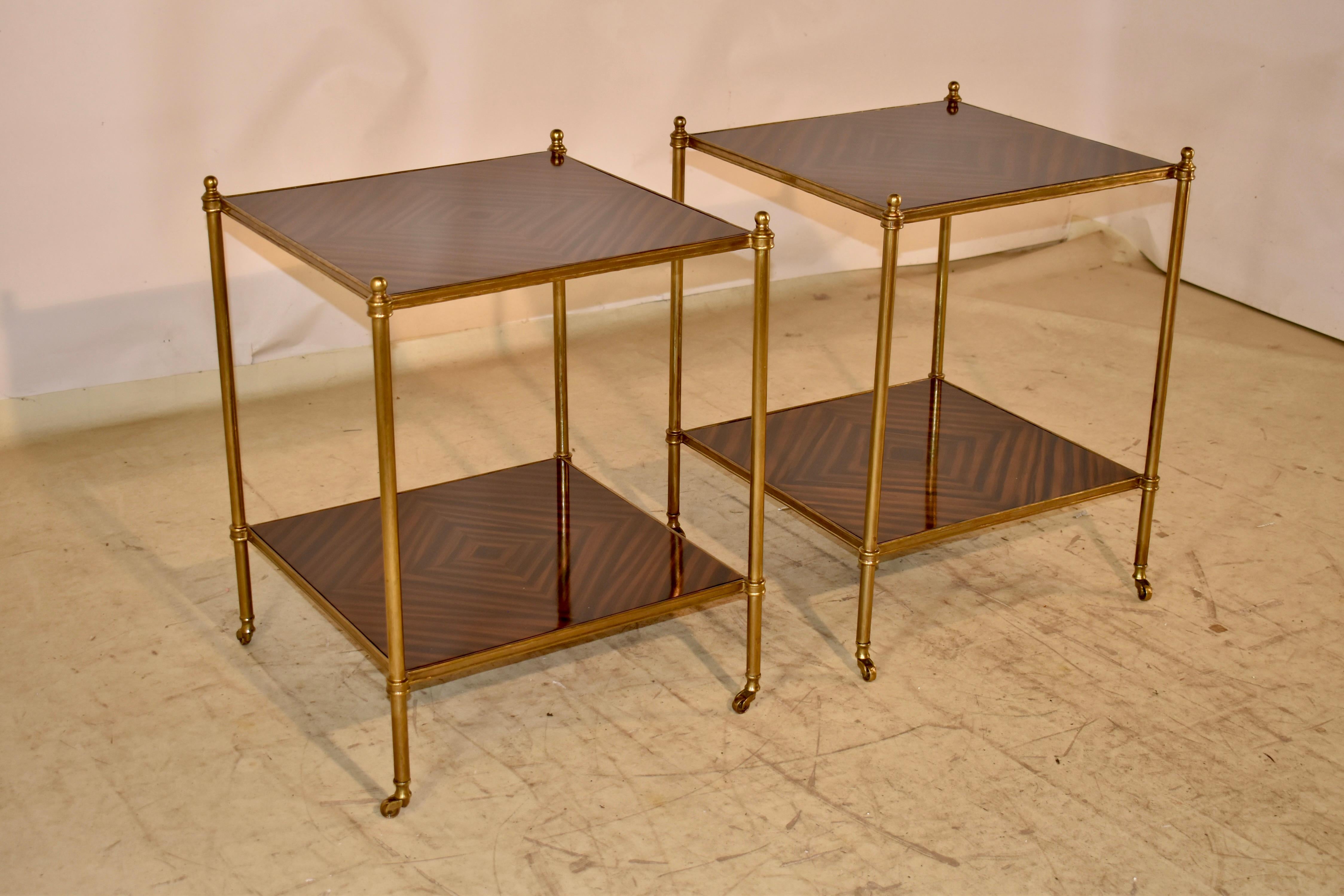 Coppia di eleganti tavolini moderni di metà secolo provenienti dalla Francia.  I telai dei tavoli sono realizzati in ottone e presentano dei terminali agli angoli superiori.  Le gambe sono semplici e sono collegate da ripiani superiori e inferiori. 