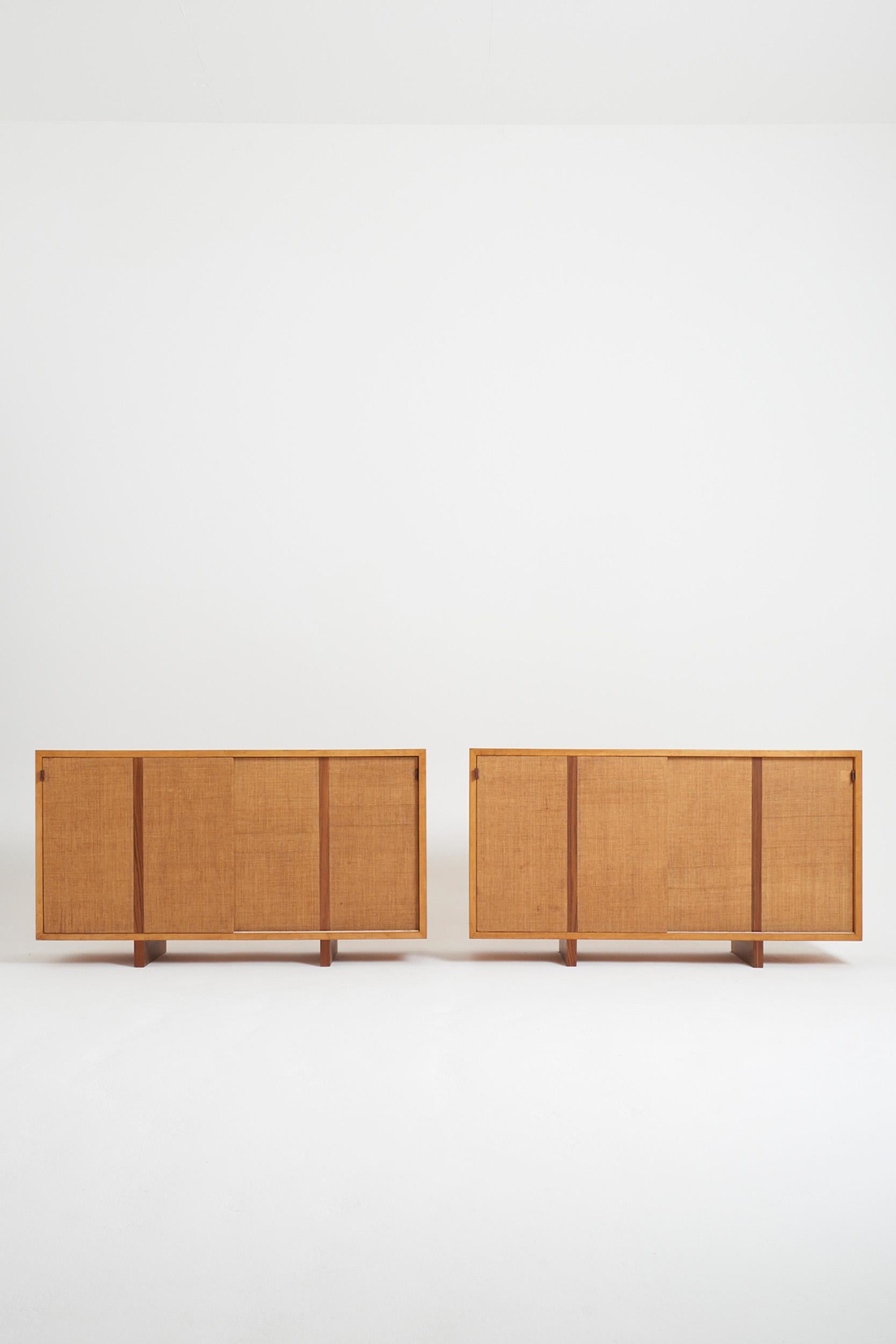 A pair of ash and hessian sideboards, the sliding doors opening with leather handles. 
Spain, 1970s
145 cm wide by 80 cm high by 42 cm deep 

Provenance: Former headquarters of the publishing house Gustavo Gili, building designed in 1953, by
