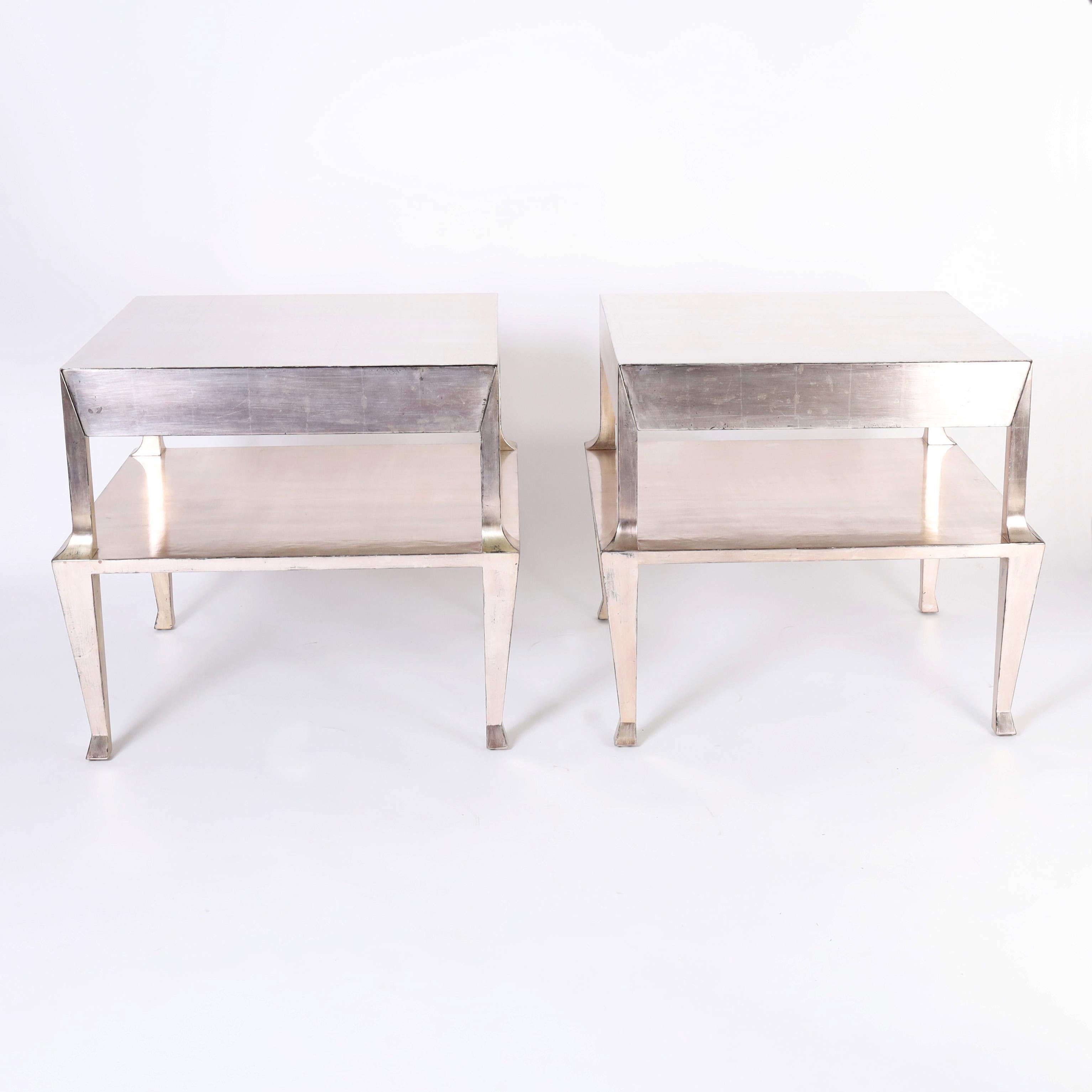 Chic pair of mid century stands crafted in hardwood with one drawer, having a silver leaf finish over a modern neoclassic form. Manufactured by Therien Studio Workshops. 