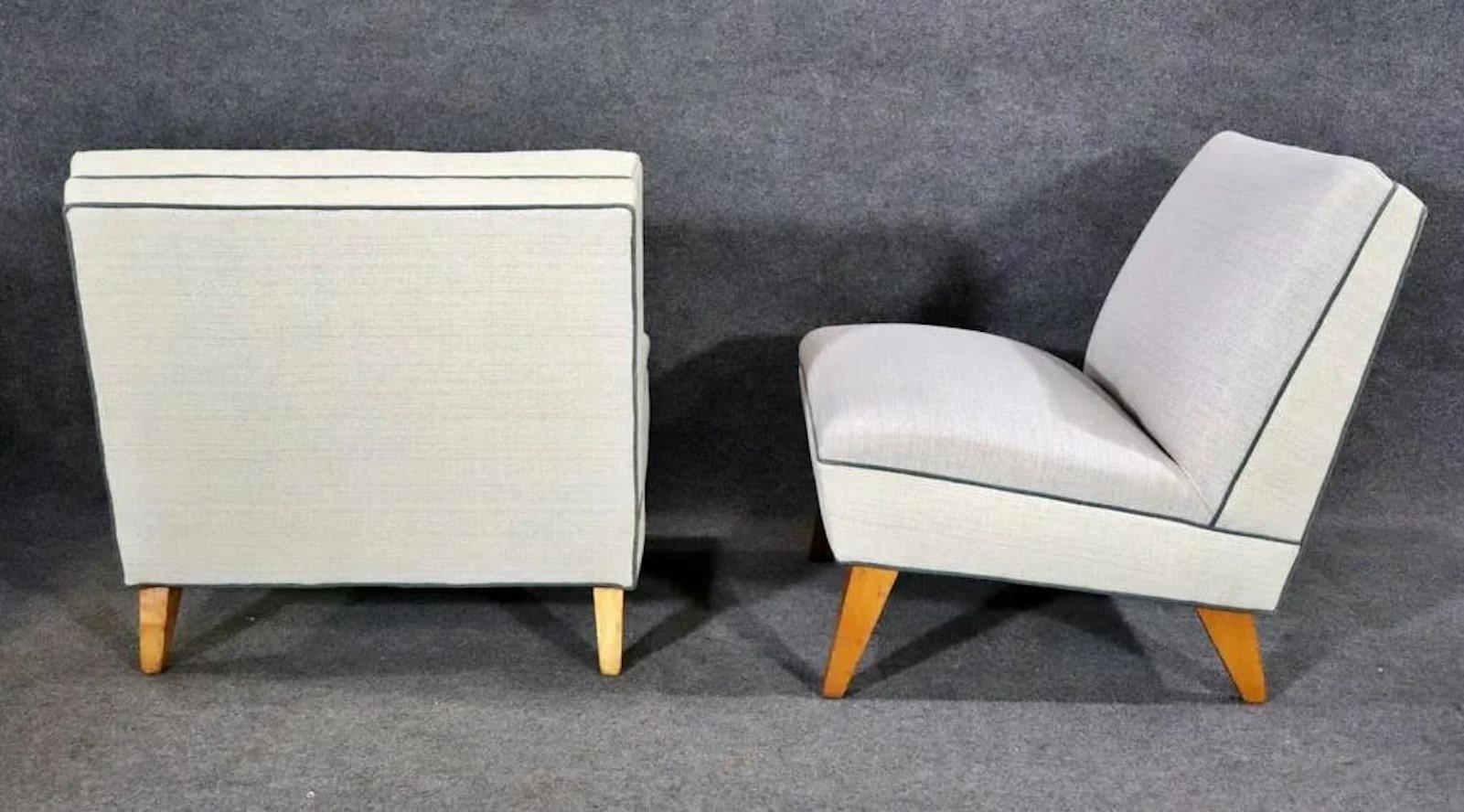 Pair of slipper chairs with wood legs peeking through the all fabric chairs. Blue piping around the off white fabric.
Please confirm location NY or NJ.