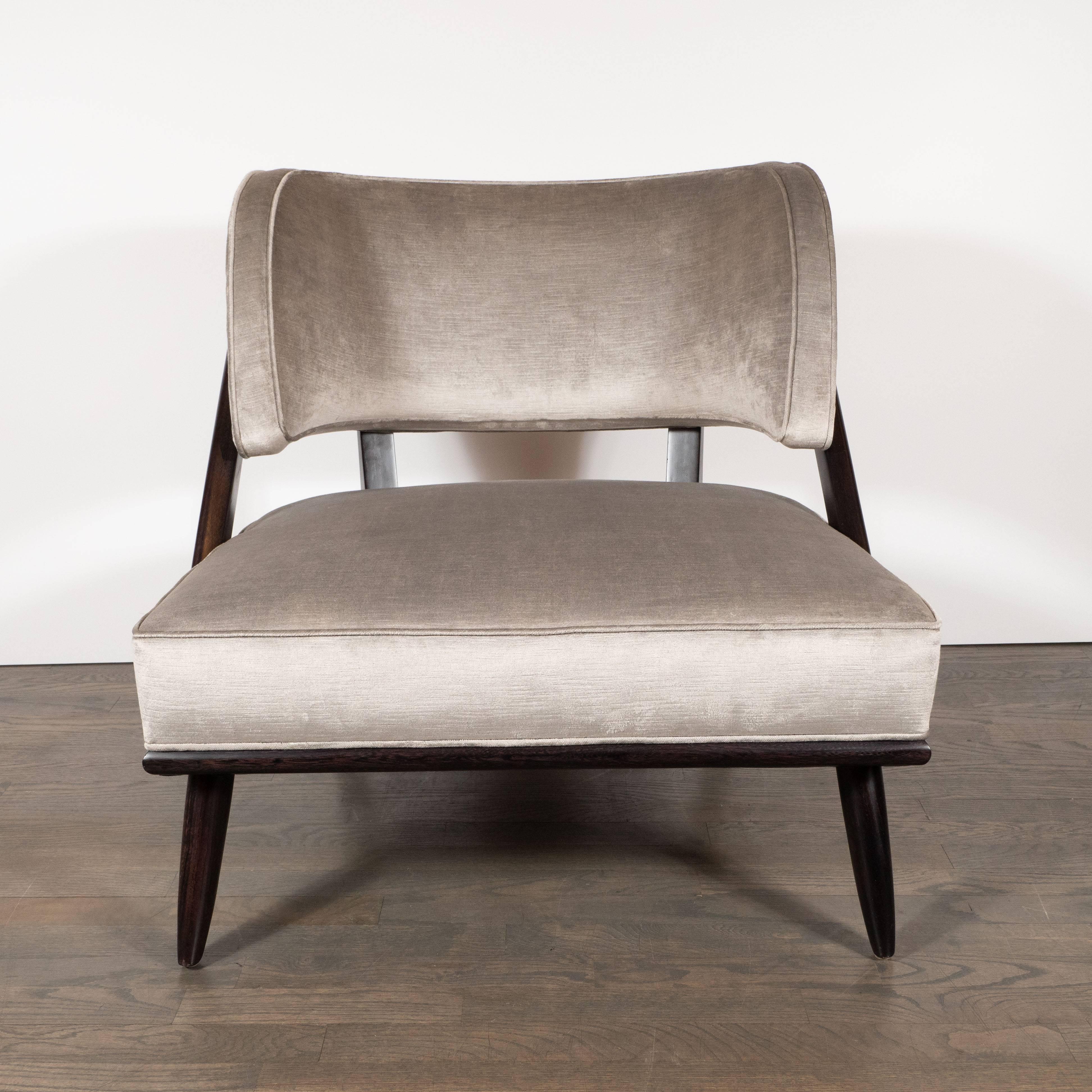 This sculptural pair of Mid-Century Modern slipper chairs were realized by the celebrated American designer and architect T.H. Robsjohn-Gibbings, circa 1950. They feature a gently curved back, splayed legs and a curvilinear frame with two vertical