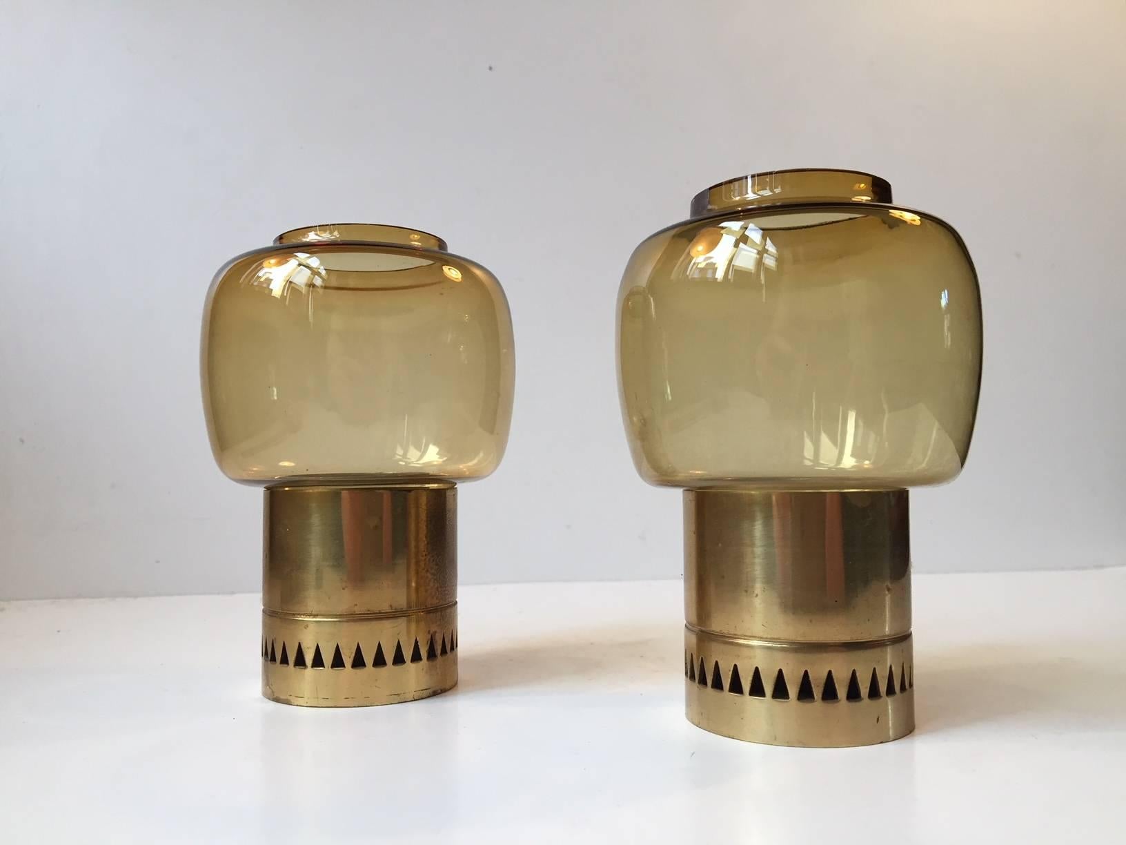 This matching pair of tea light candleholders in honey-colored smoke glass and partially perforated brass were designed by Hans-Agne Jakobsson and manufactured by Markaryd AB in Sweden during the 1960s.