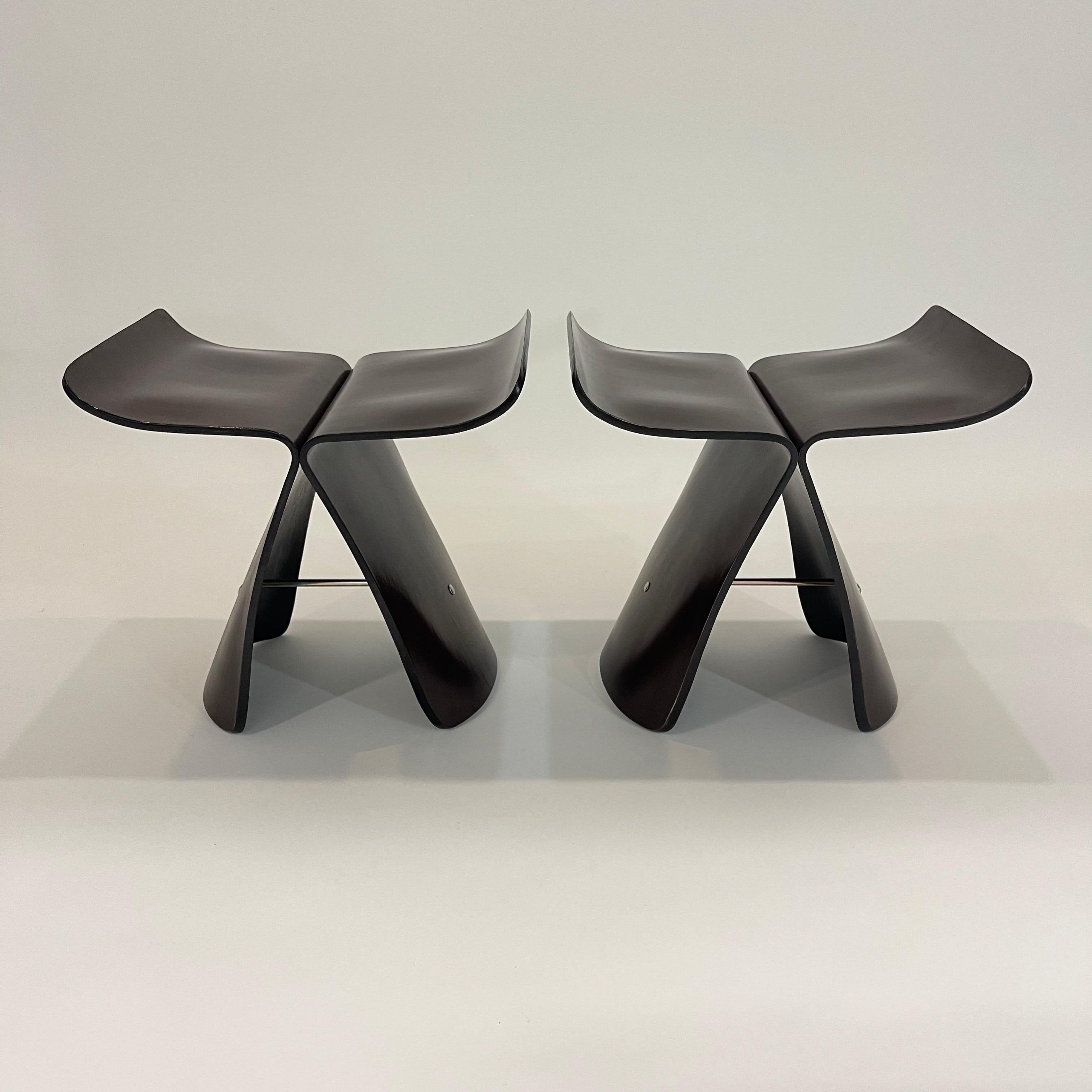 Pair of iconic midcentury butterfly stools rendered in steam bent plywood wrapped in a Japanese wood paper veneer with black painted edges and underside, attached with metal hardware.  Attributed to Sori Yanagi for Tendo Mokko.