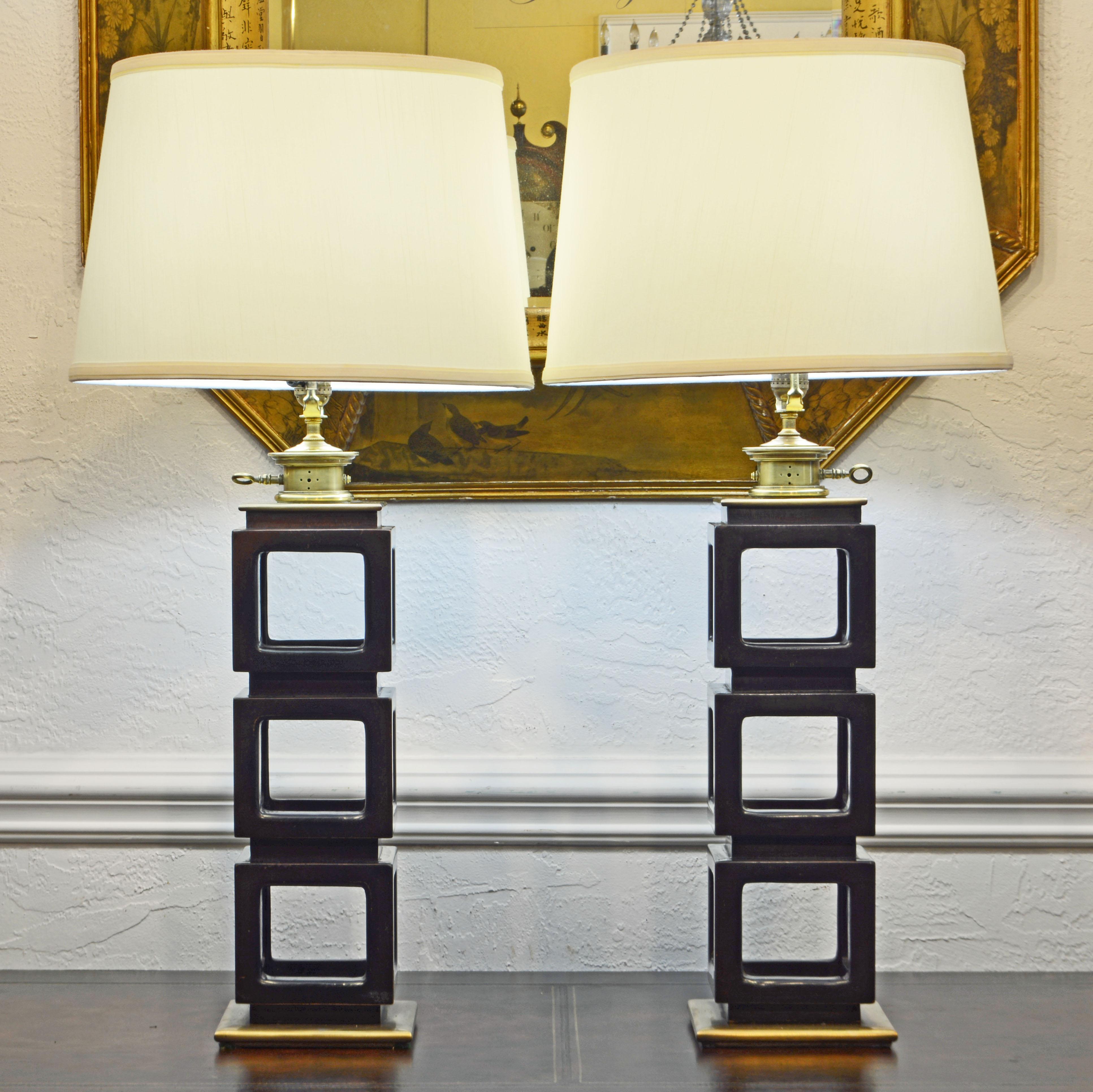 These lamps are of an oriental influenced modernist design consisting of three carved open mahogany cubes with brass round edge top plates and light fixtures resting on round edge brass bases. They are sold without shades for ease of shipping.