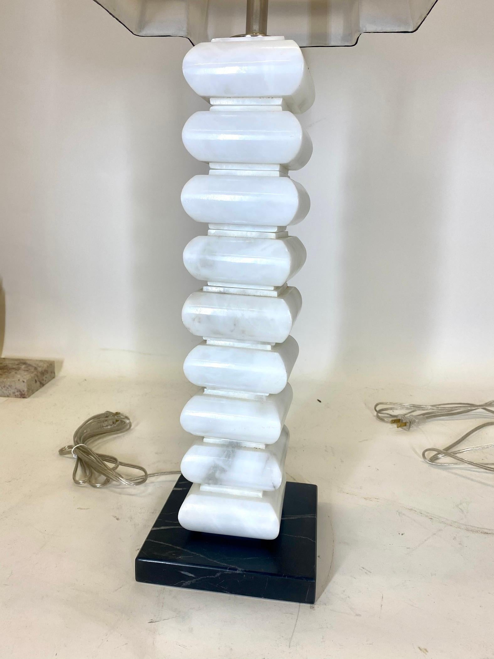 A pair of white marble stacked lamps on custom black Lucite bases. Newly rewired. Marble stacks were made in the 1950s in Italy. Lamps come with white and black trimmed shades and black glass finials.

Dealer: R316TF.