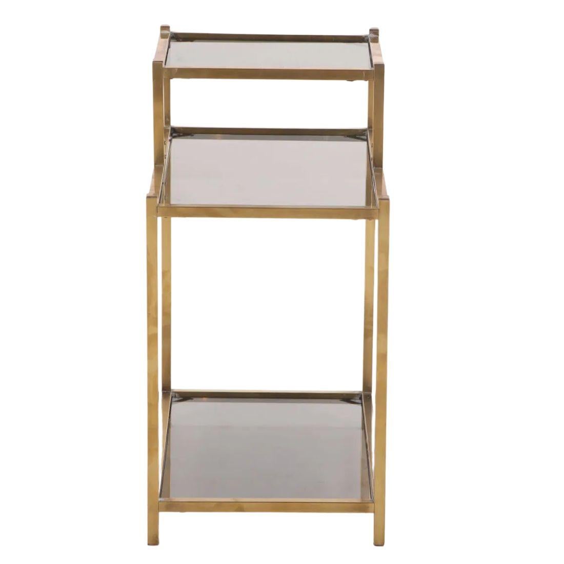 Cette élégante paire de tables d'appoint, fabriquée dans les années 1970, allie la sophistication élégante du laiton à l'allure moderne du verre fumé. Chaque table présente un cadre en laiton de forme carrée avec trois niveaux distincts, mettant en