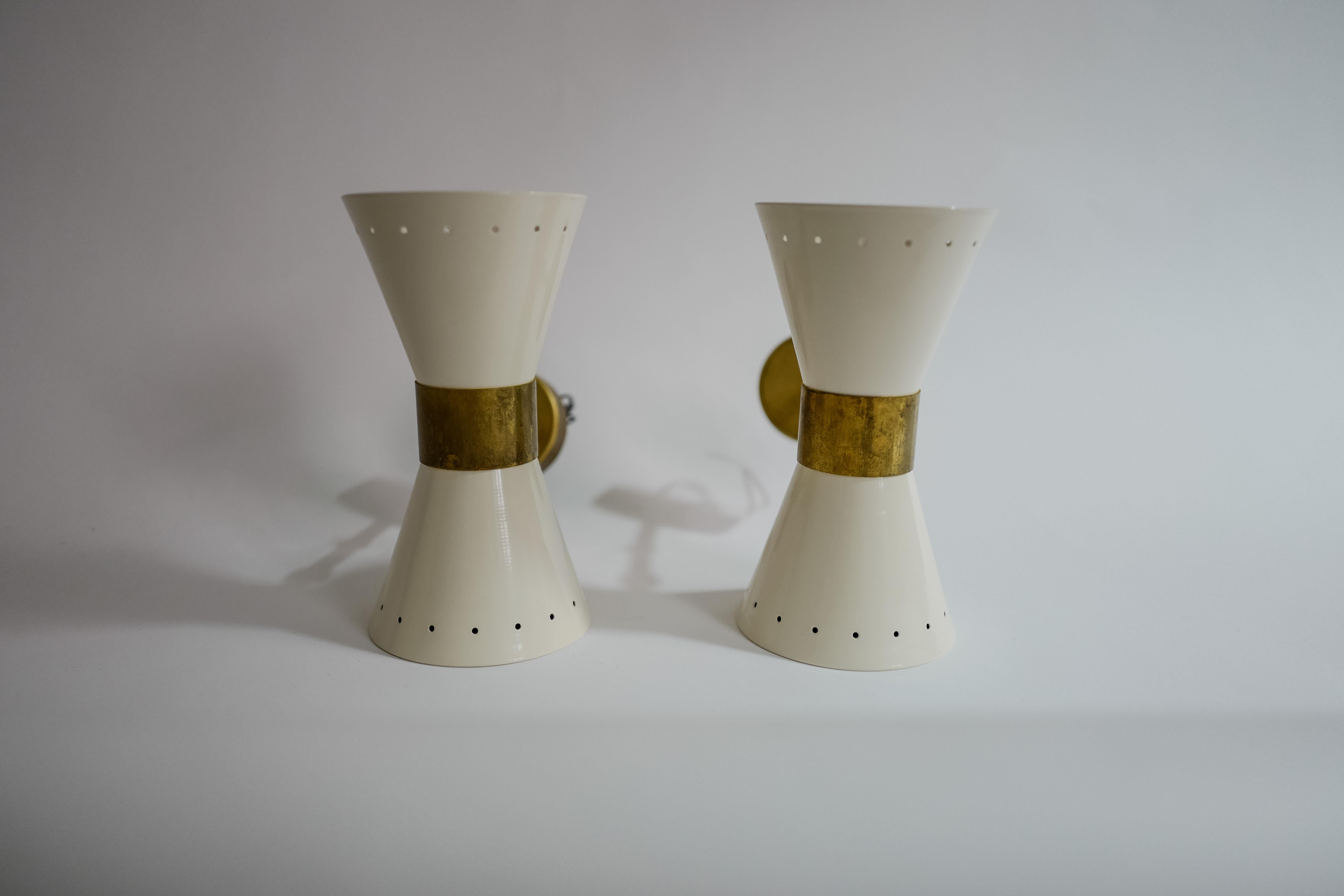 An elegant vintage pair of mid-century Stilnovo model Diabolo painted white metal and brass wall sconces, 1960’s Italy. Wired for Europe.