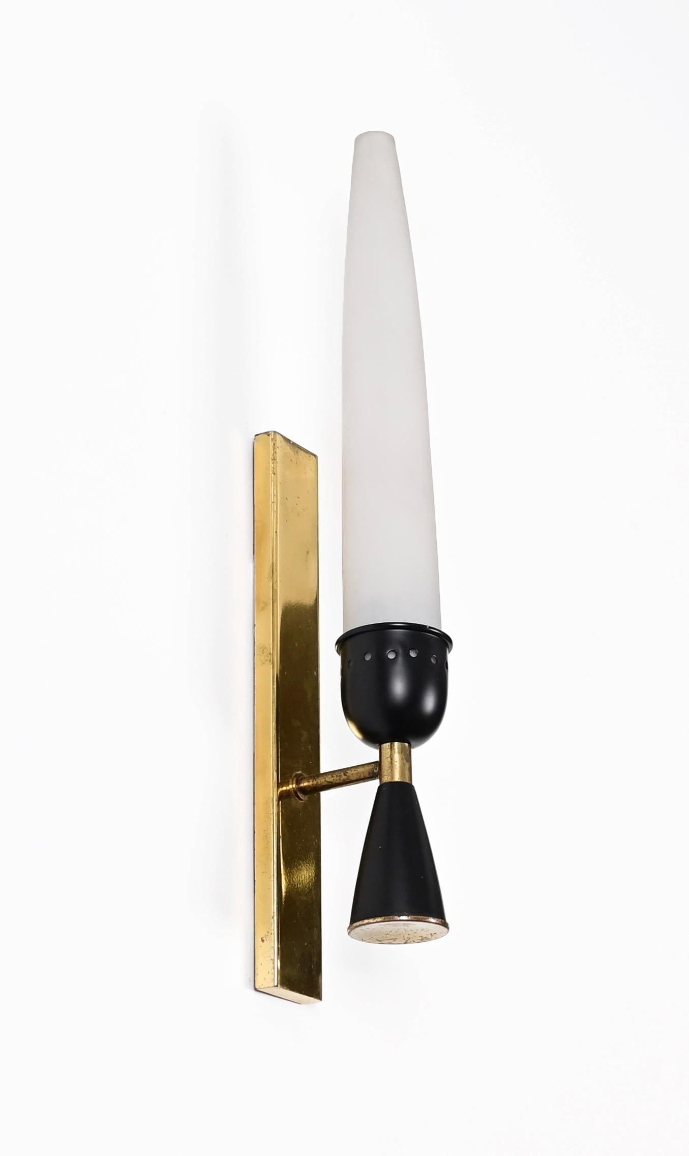 Fantastic pair of Mid-Century sconces in solid brass and opaline glass. This stunning wall lamps were designed by Stilnovo in Italy during the 1950s. 

This gorgeous sconces have a plate in solid brass with the arm in enameled black metal with brass