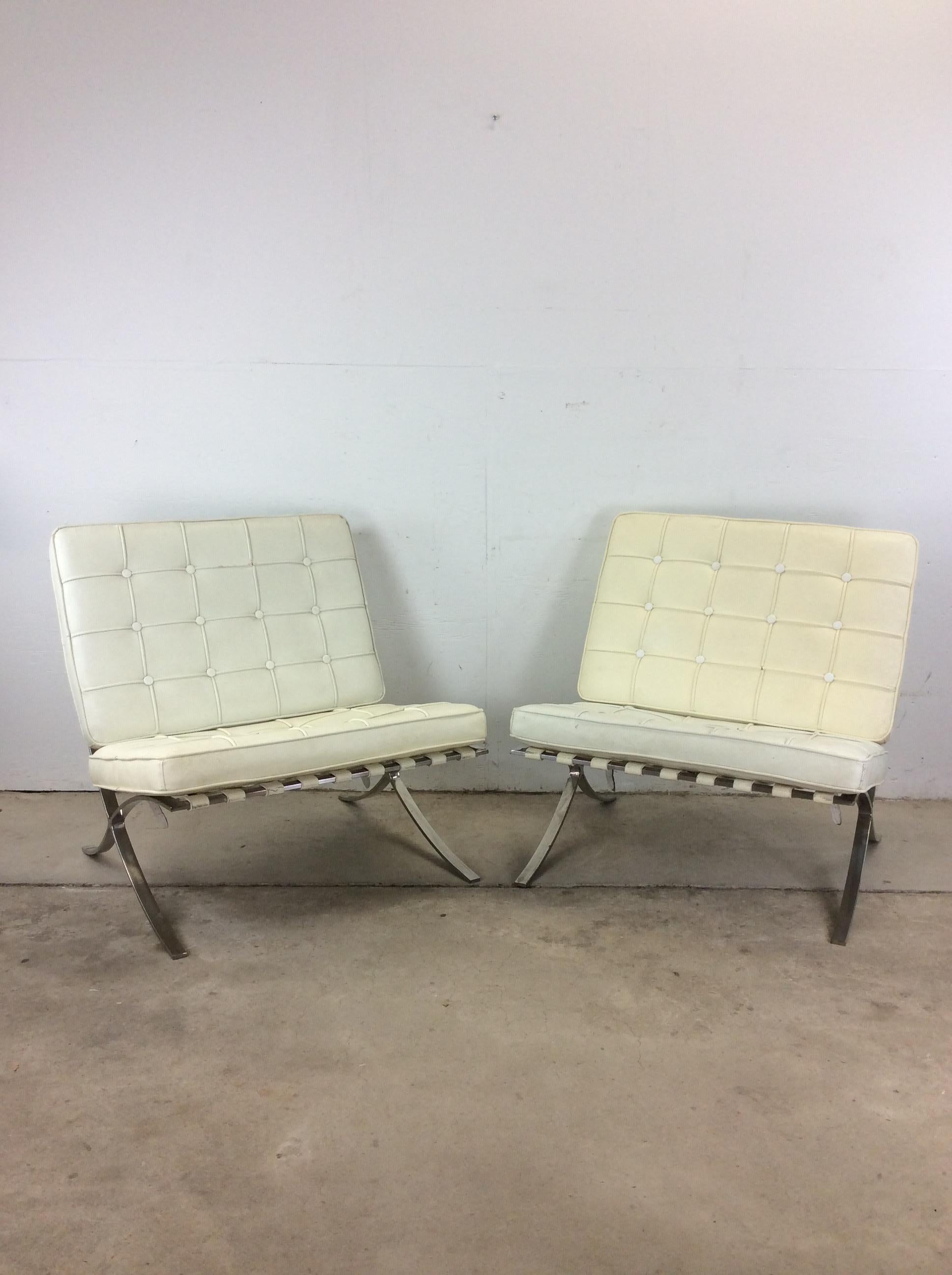 This pair of mid century lounge chairs styled after the Barcelona chair attributed to Mies van der Rohe feature polished chrome frame, leather band seat supports, and two white leather removable seat cushions.

Dimensions: 31w 30.5d 32h