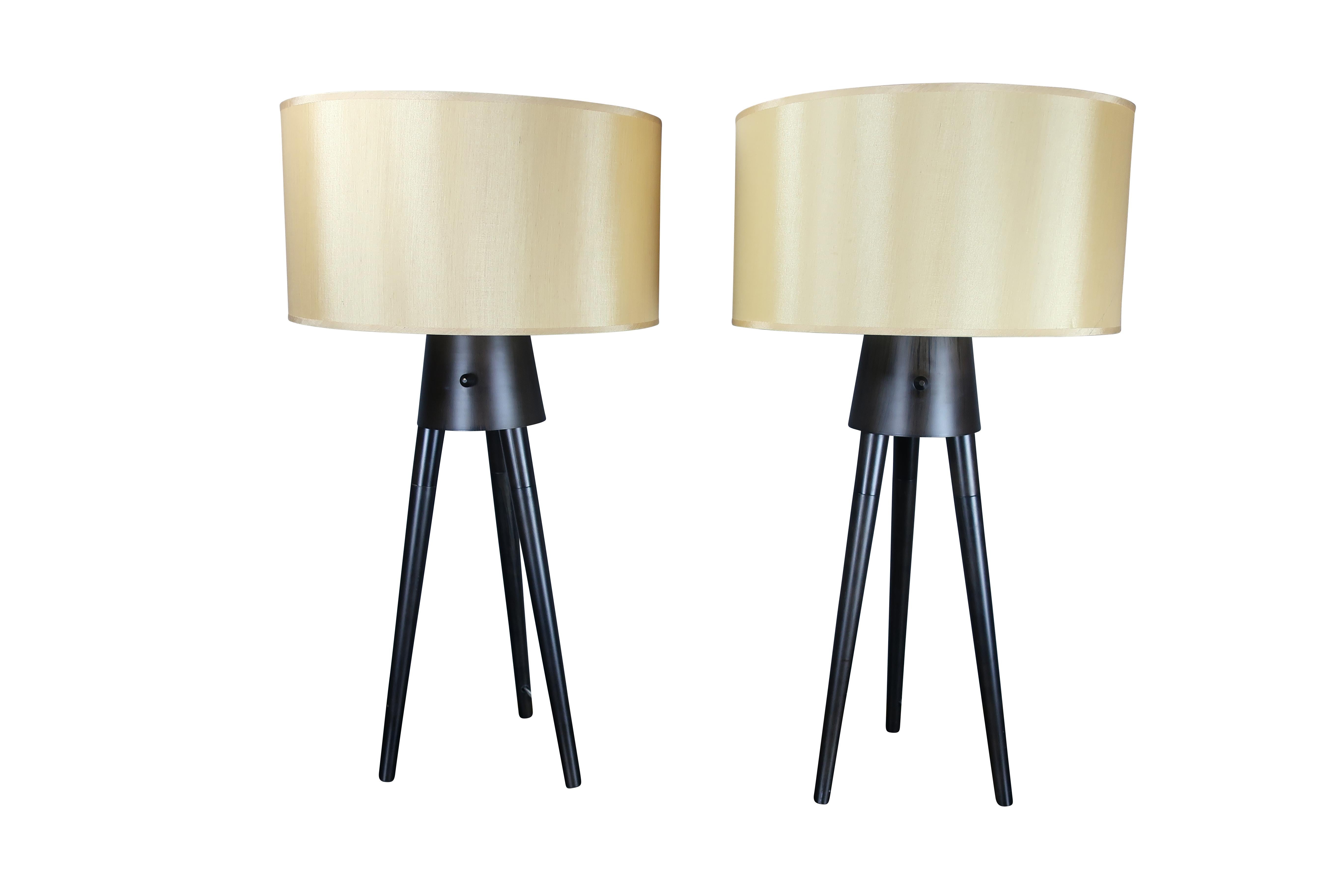 Pair of midcentury black metal tripod lamps with Champagne shades.