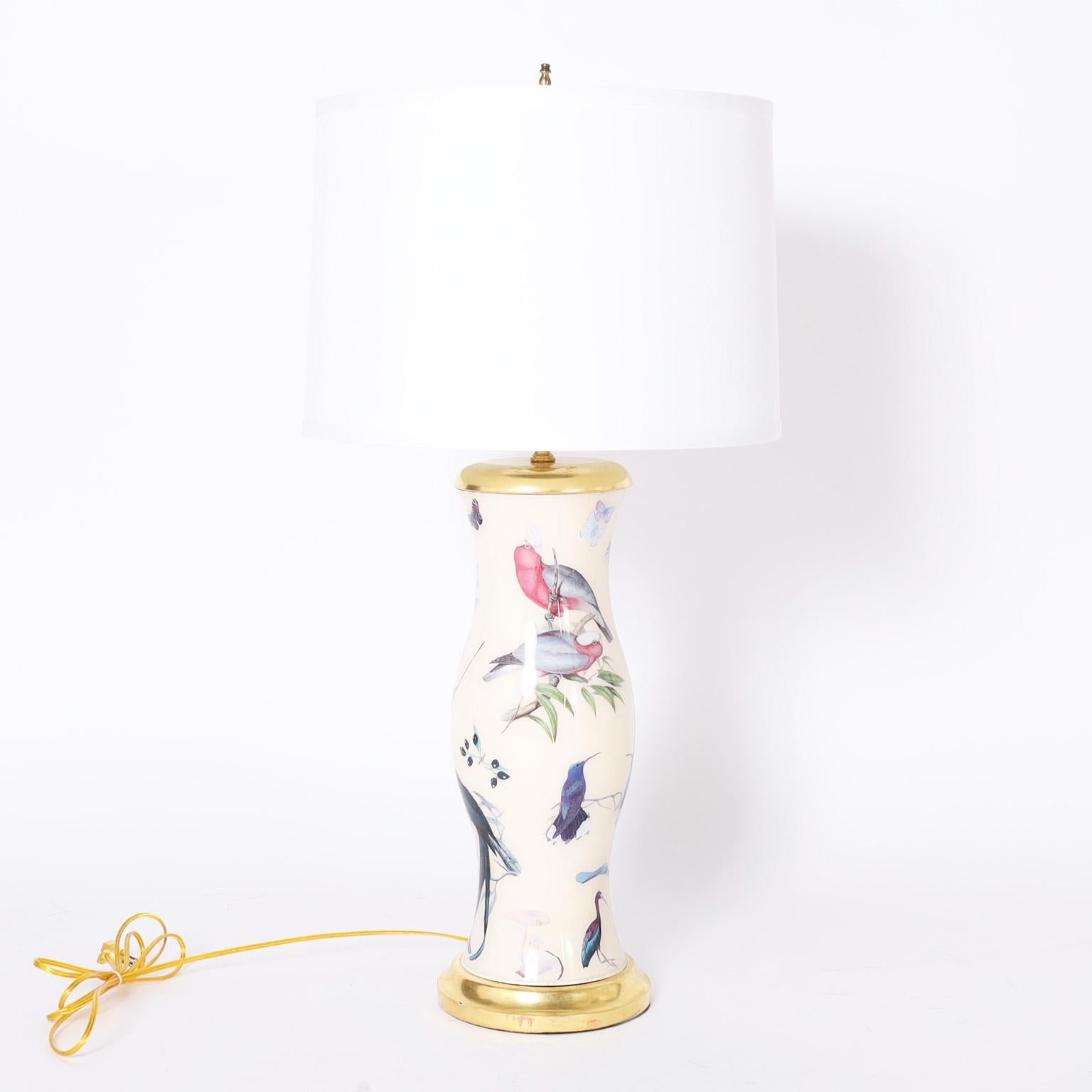 Standout pair of table lamps crafted in glass in a classic form featuring a reverse decoupage technique with birds, bugs and berries presented in brass hardware.