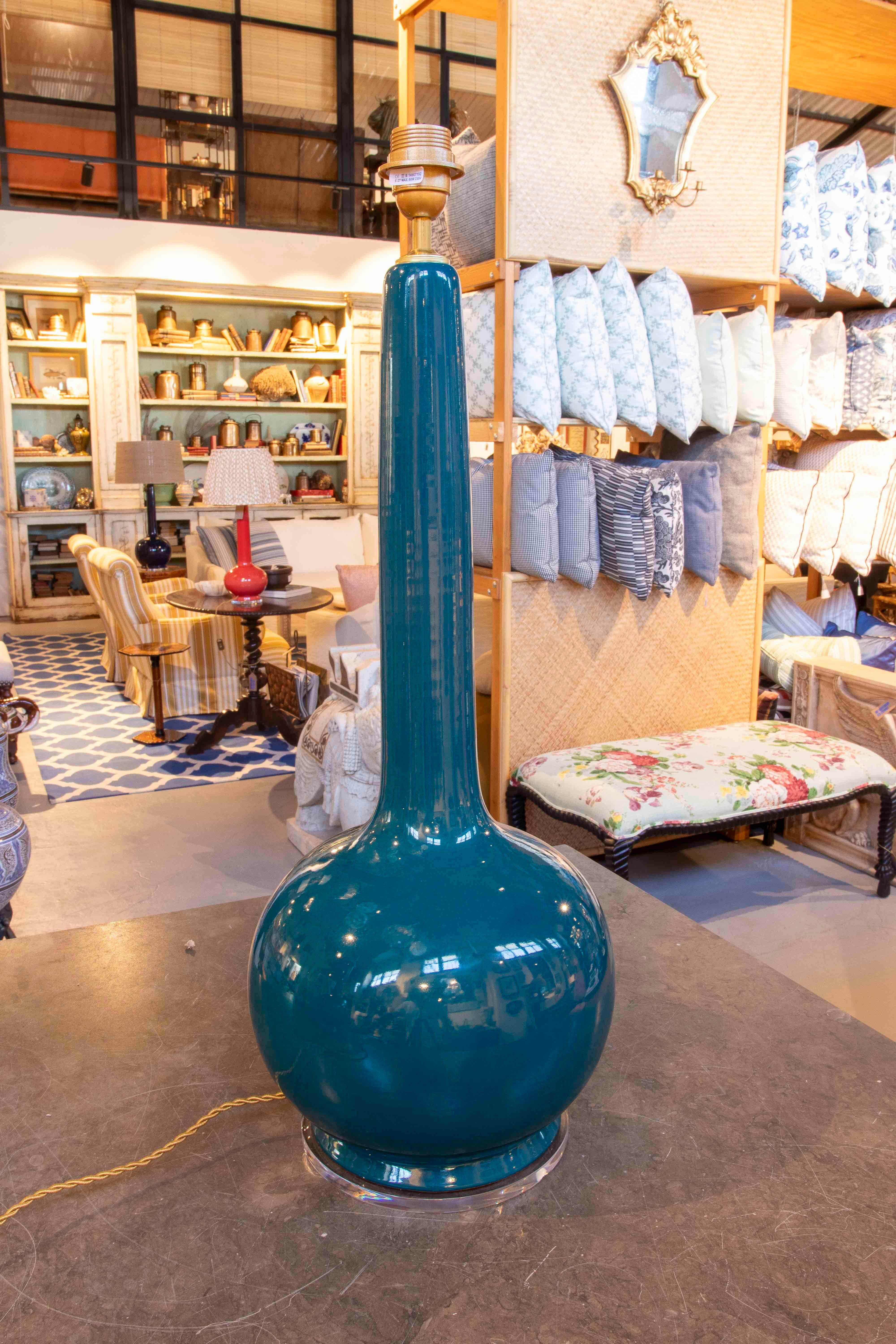 A stunning pair of table lamps crafted from glazed ceramic in a deep green hue, with a glossy glaze finish that enhances their elegance and decorative character. The design combines a globular base with an elongated, slender neck, evoking the