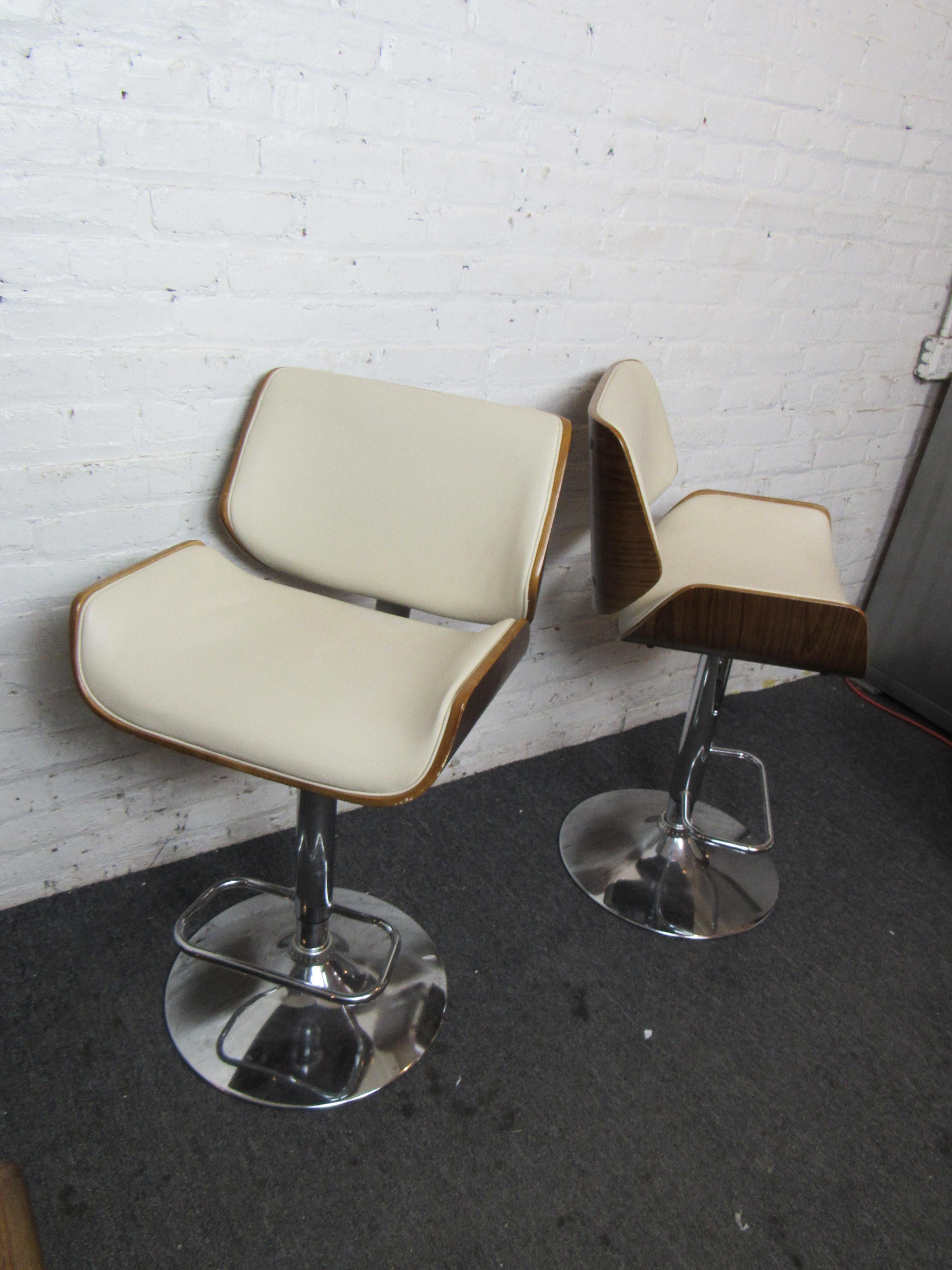 A beautiful Mid-Century Modern pair of barstools that combine unique seats of walnut and vinyl with chrome bases. The seats are adjustable from a seat height of 25