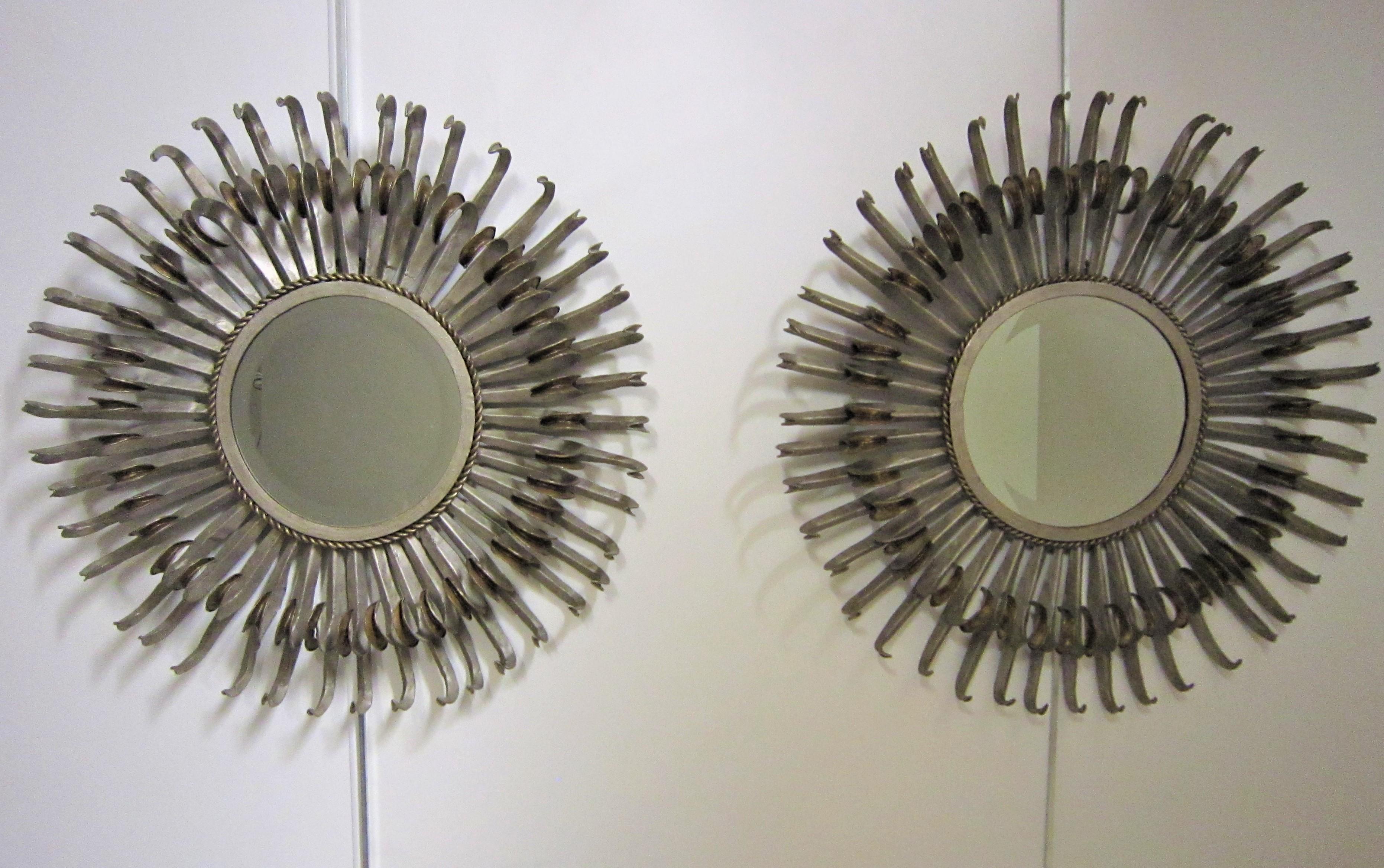Paire originale de miroirs à rayons bicolores français à deux niveaux.
Des bords en cils recourbés en feuille d'argent et en fer doré foncé patiné ornent ce miroir soleil.
Le miroir central biseauté d'origine est entouré d'un détail tressé