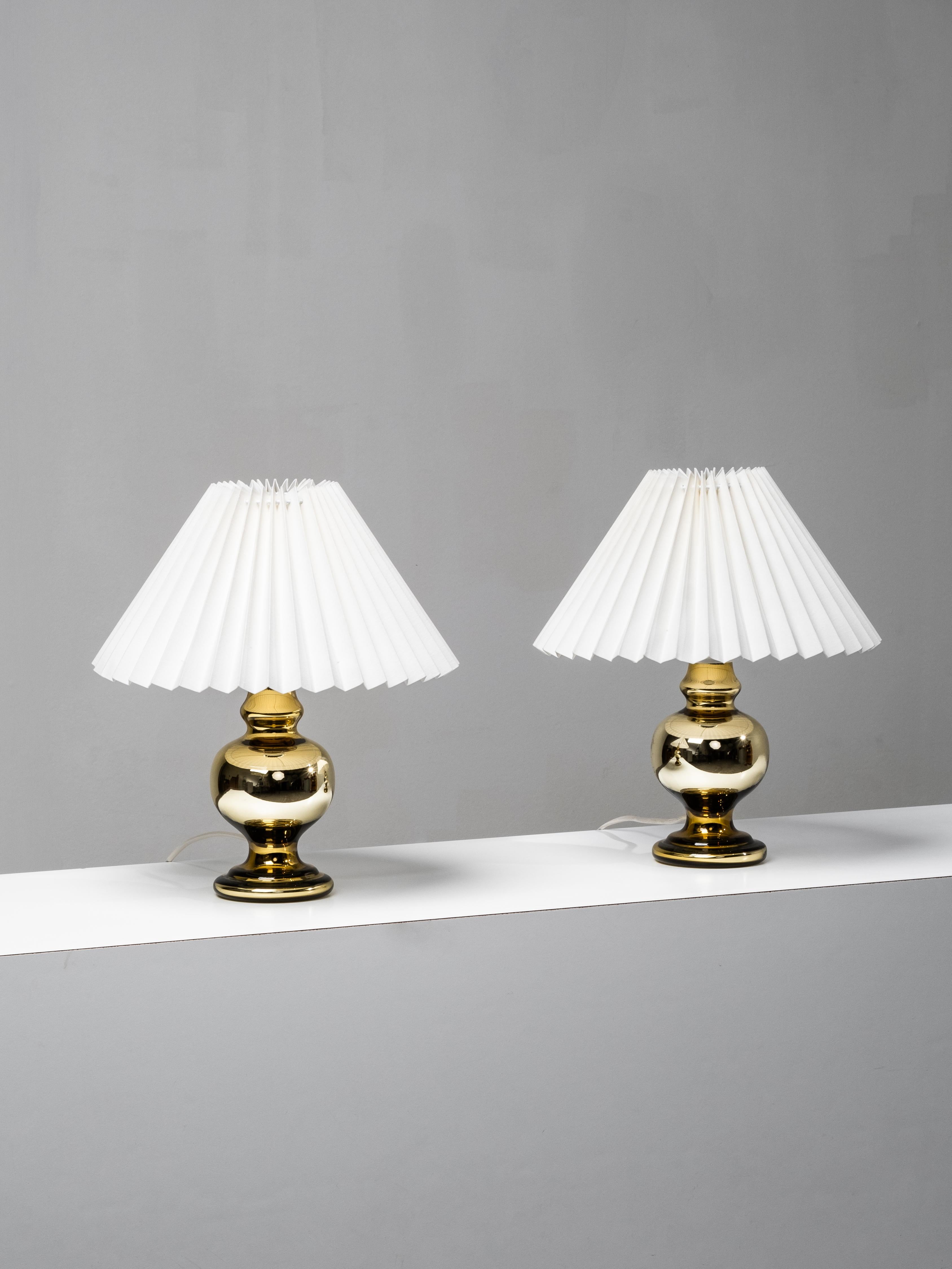 Charming pair of Swedish mid-century table lamps from the 1960s, featuring gold-tinted mercury glass bases with a smooth, reflective surface. The voluptuous form and warm metallic sheen give these lamps a distinctive yet timeless presence.

Each