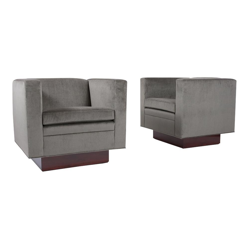 This Pair of Mid-Century Modern 1960s Swivel chairs have been professionally restored and features a sleek cube, flat back, and armrest design. These lounge chairs have been professionally upholstered in a new grey color mohair velvet fabric with