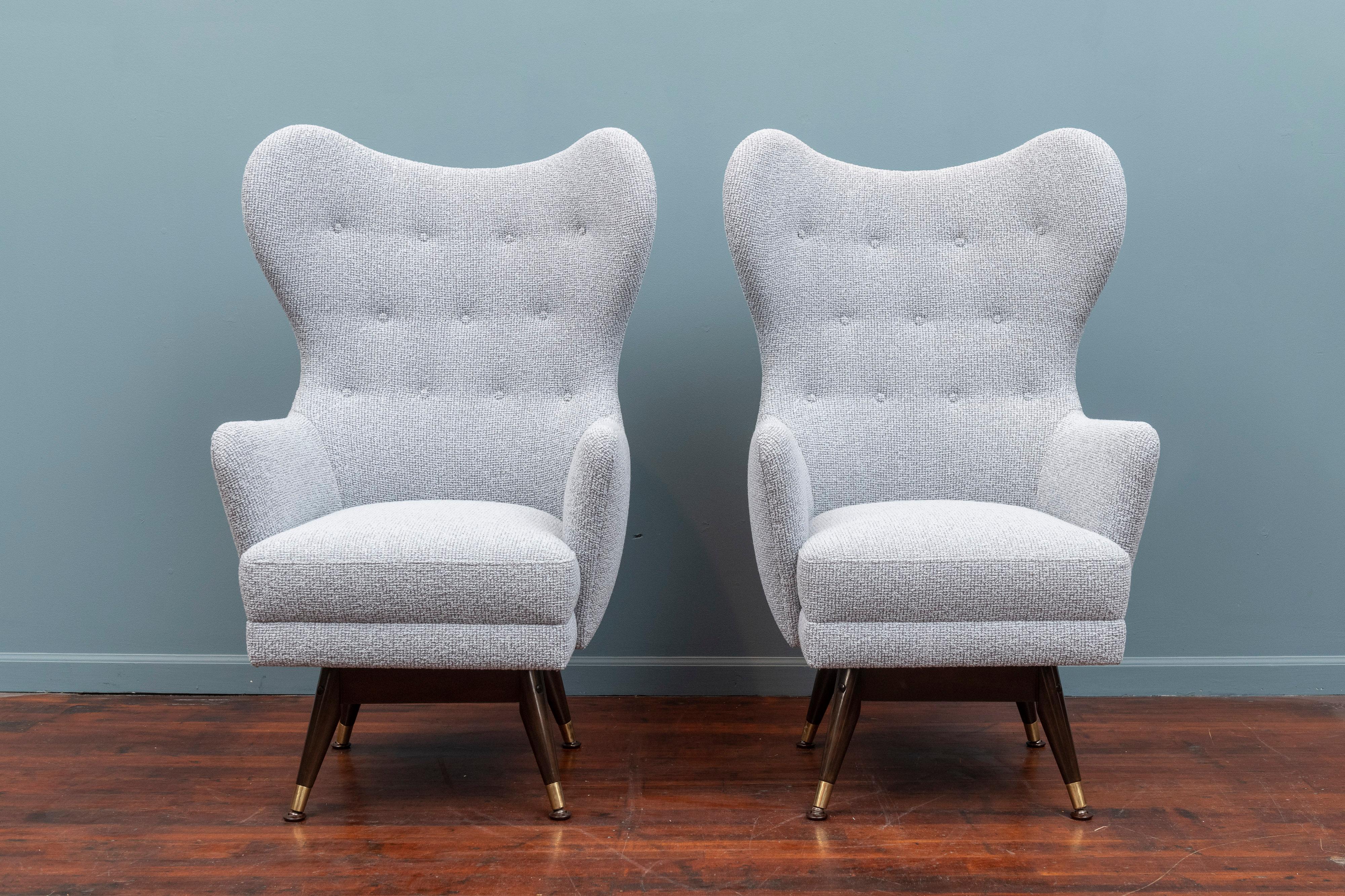 Pair of midcentury swivel lounge chairs on refinished and polished mahogany and brass bases. Newly upholstered in Maharam pebble wool.
