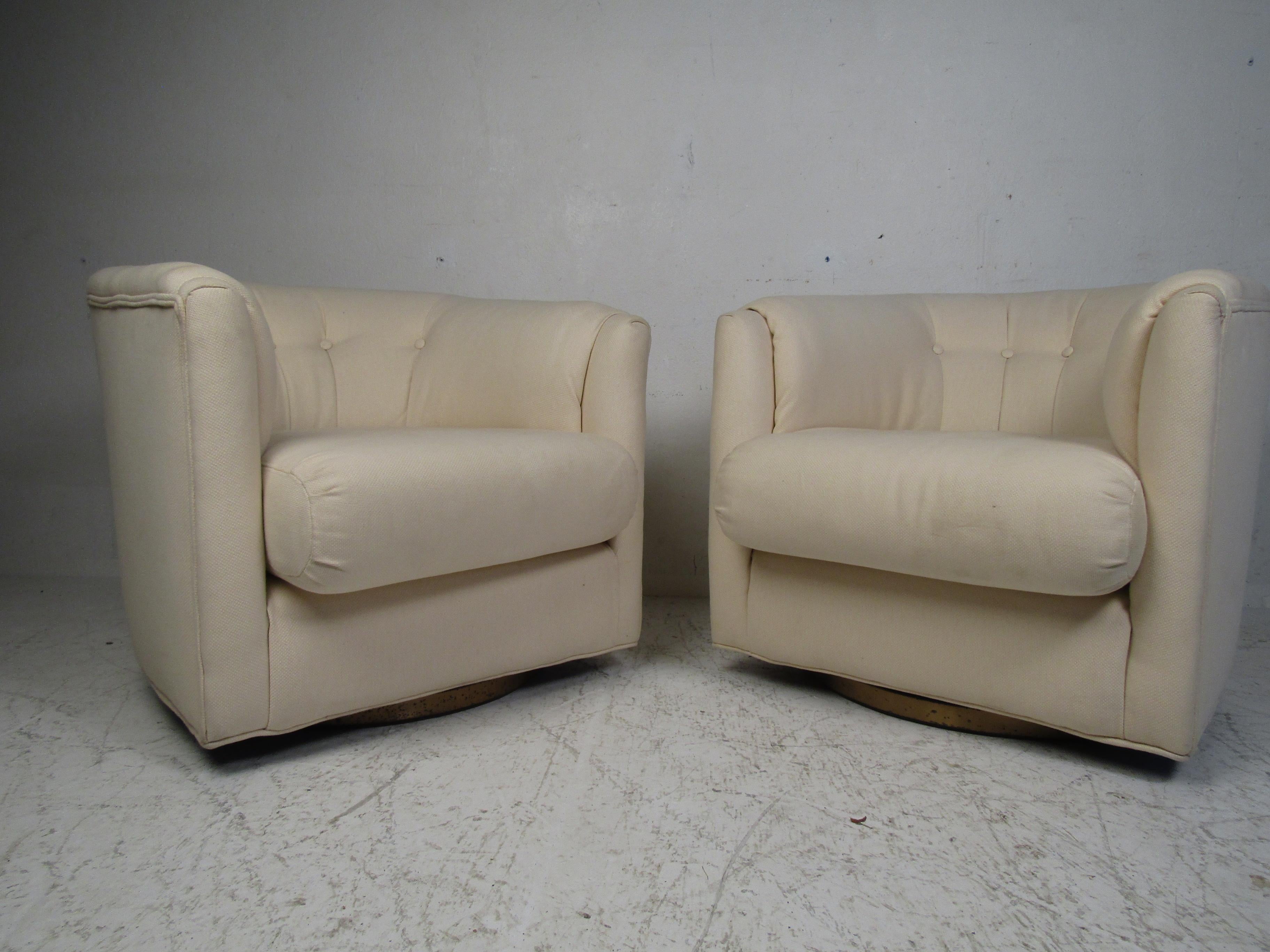 A stylish pair of vintage modern barrel back chairs with a tufted backrest and a thick padded seat. A brass swivel base offers convenience without sacrificing style. This pair of lounge chairs make the perfect addition to any home, business, or