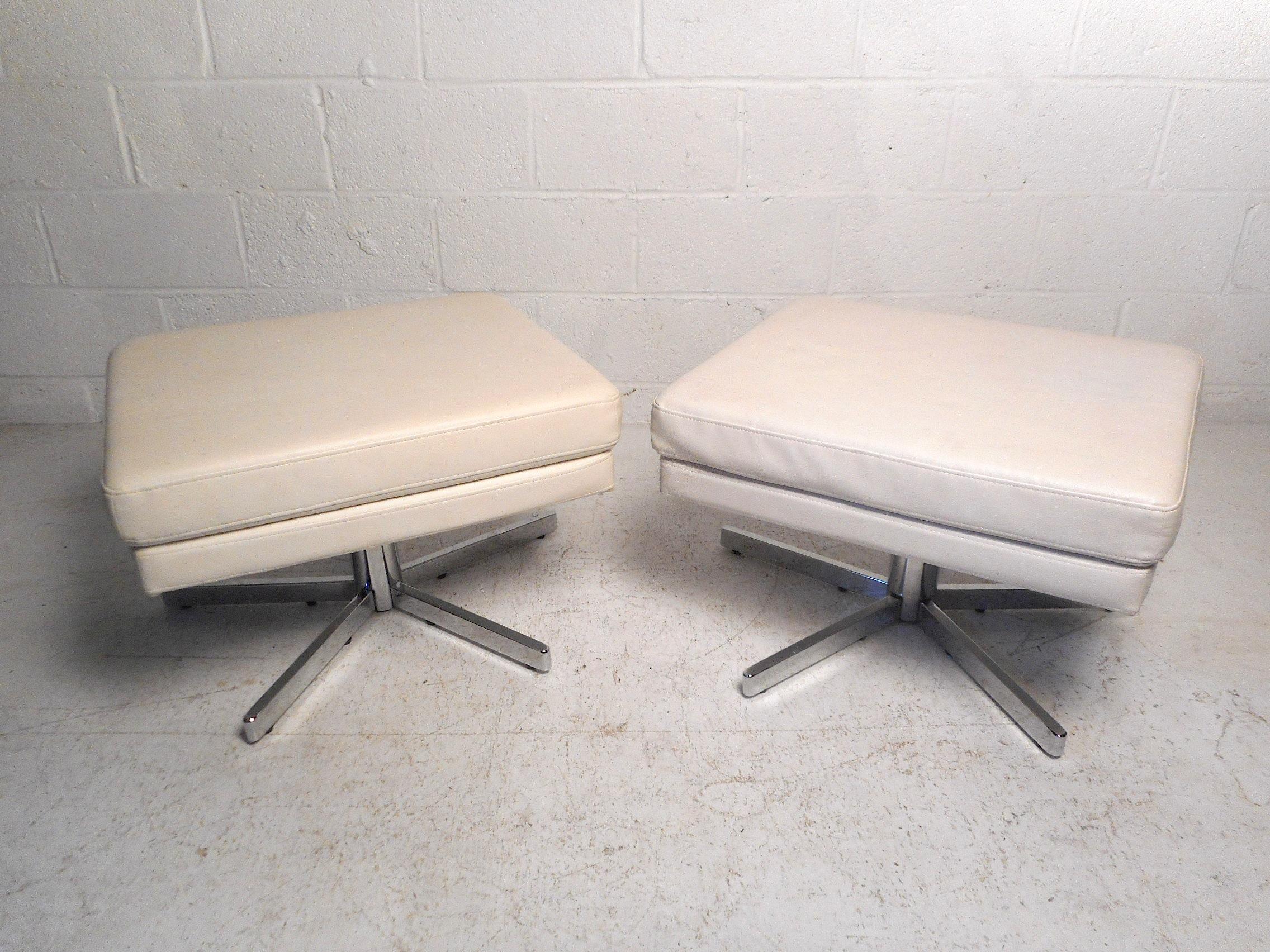 This impressive pair of midcentury ottomans feature a sleek white faux-leather upholstery, vibrant chrome swivelling bases, and comfortable soft cushioning. A distinctive midcentury set sure to please in any modern interior. Please confirm item