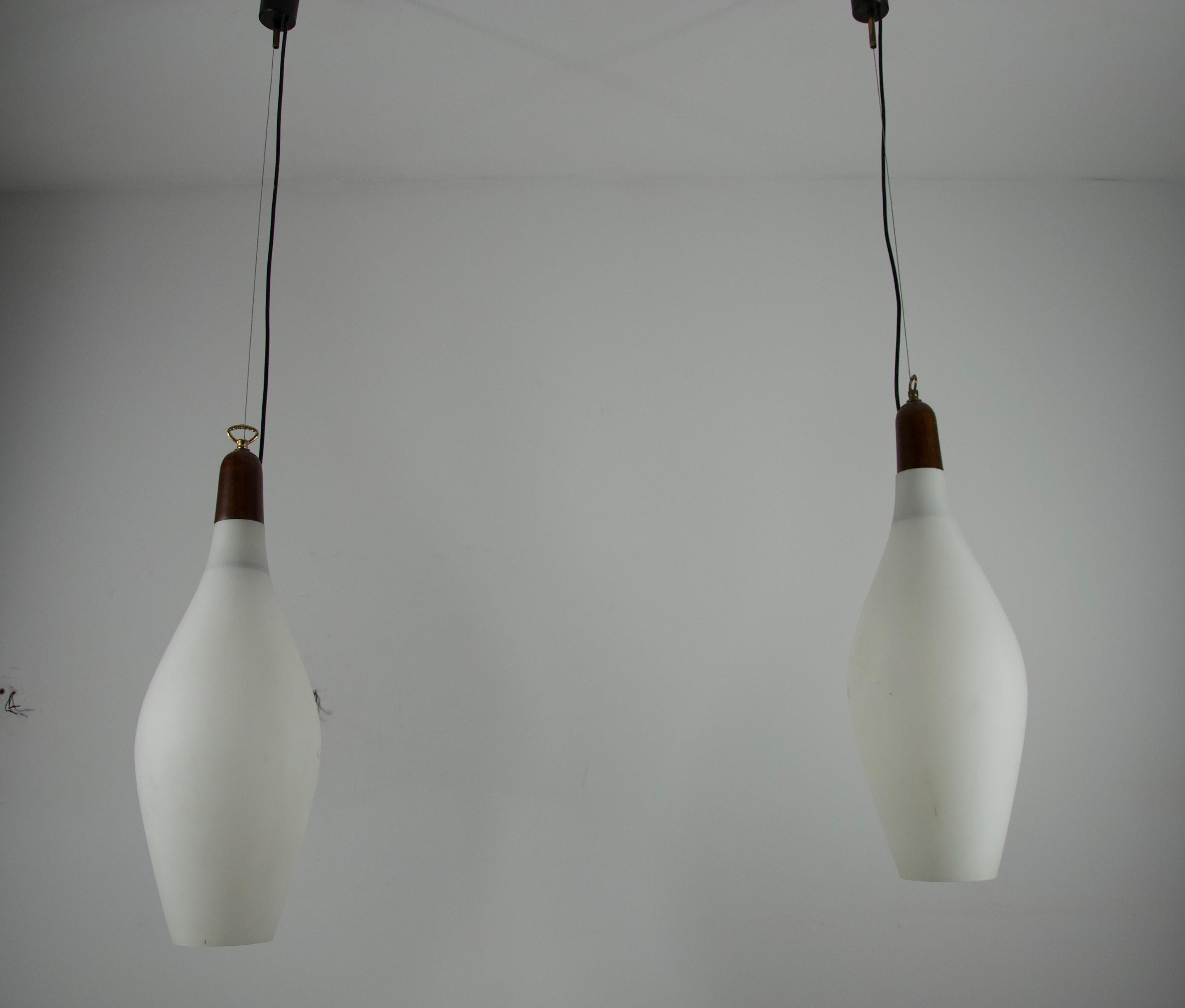 Cette élégante paire de lampes suspendues italiennes du milieu du siècle, datant des années 1960, capture parfaitement la sensibilité au design raffiné de l'époque. Chaque lampe est dotée d'un abat-jour en verre opale joliment incurvé, complété par