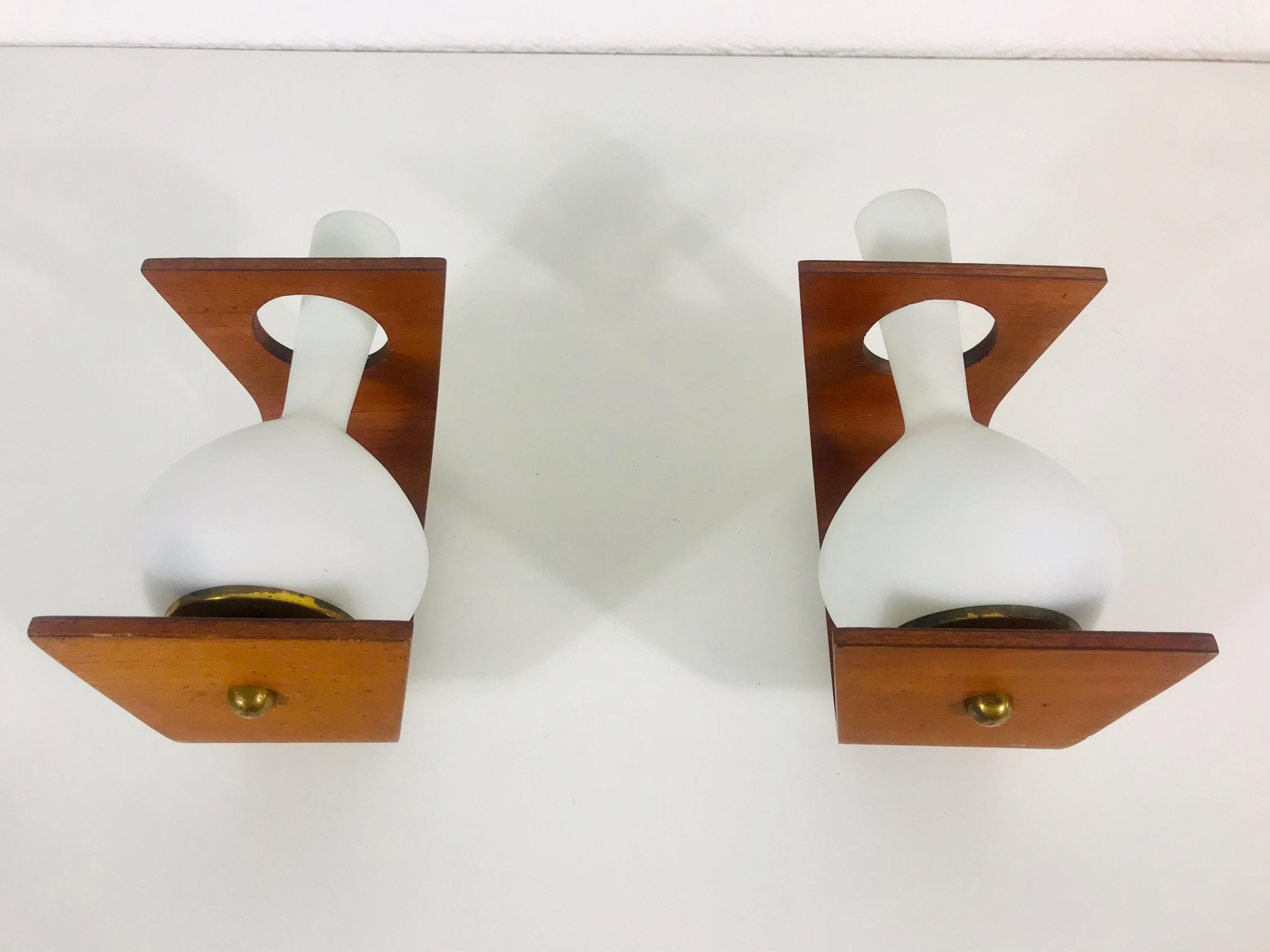 A pair of Italian wall lamps made in the 1960s attributed to Stilnovo. It is fascinating with its rare glass shape. The body of the lamp is beautiful teak wood. 

The light requires one E14 light bulbs.