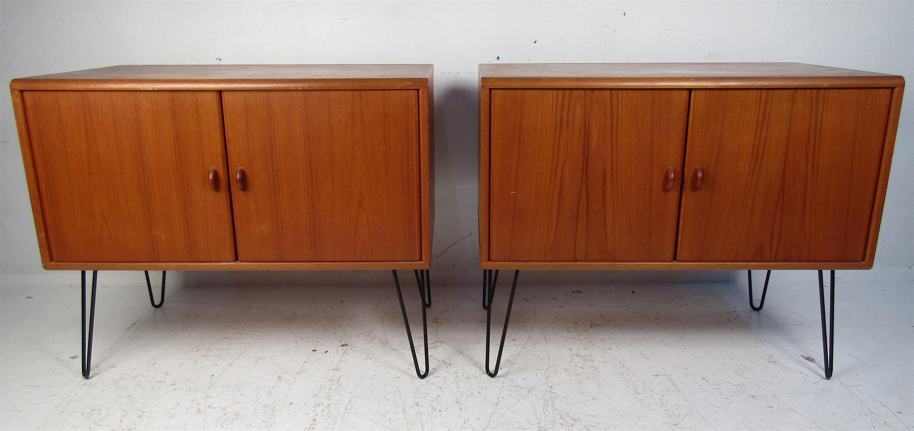 A beautiful pair of Danish teak cabinets that boast metal hairpin legs and sculpted pulls. A large compartment with a shelf offers plenty of room for storage. The rich teak finish and clean lines show quality craftsmanship. A lovely Mid-Century