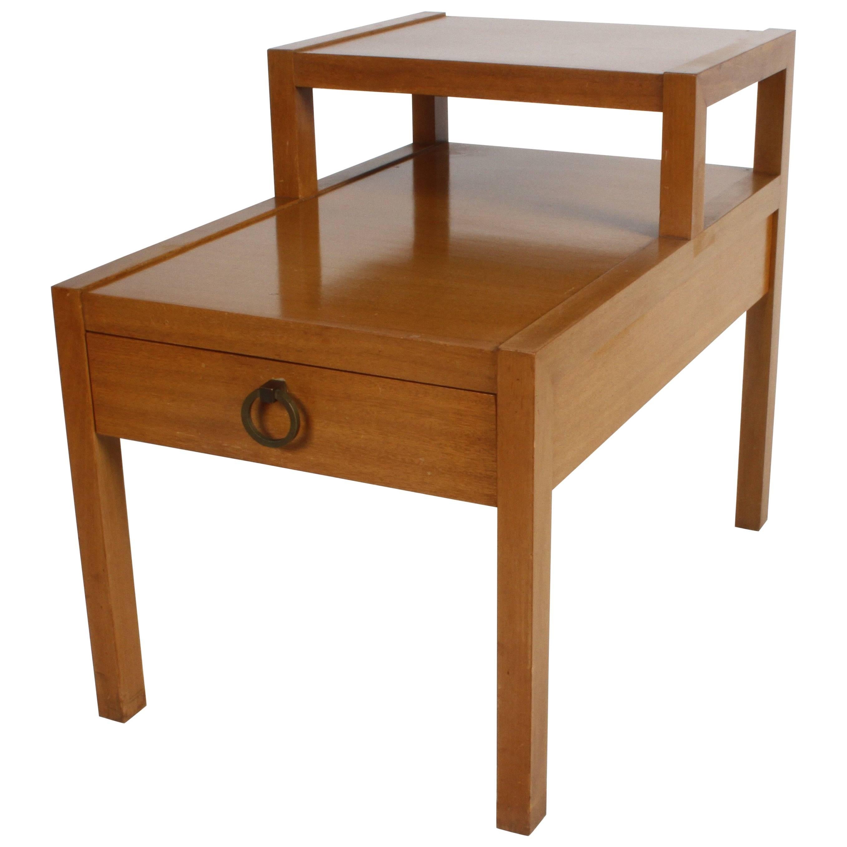 Mid-Century Modern stepped or tiered end table with drawer and brass Asian style ring pull. Original finish, shows wear. Can be refinished for additional cost. T.H. Robsjohn-Gibbings did a similar design for Widdicomb. Lower shelf is 17.25
