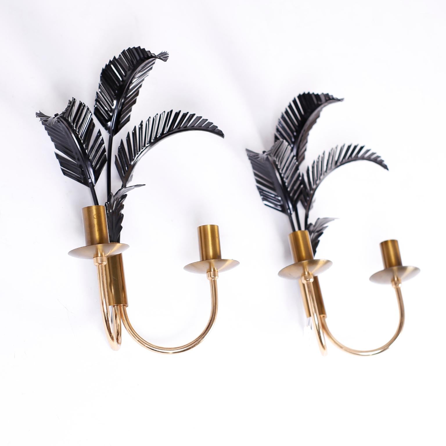 Chic pair of mid century wall sconces with black tole palm tree leaves over brass arms and candle cups.