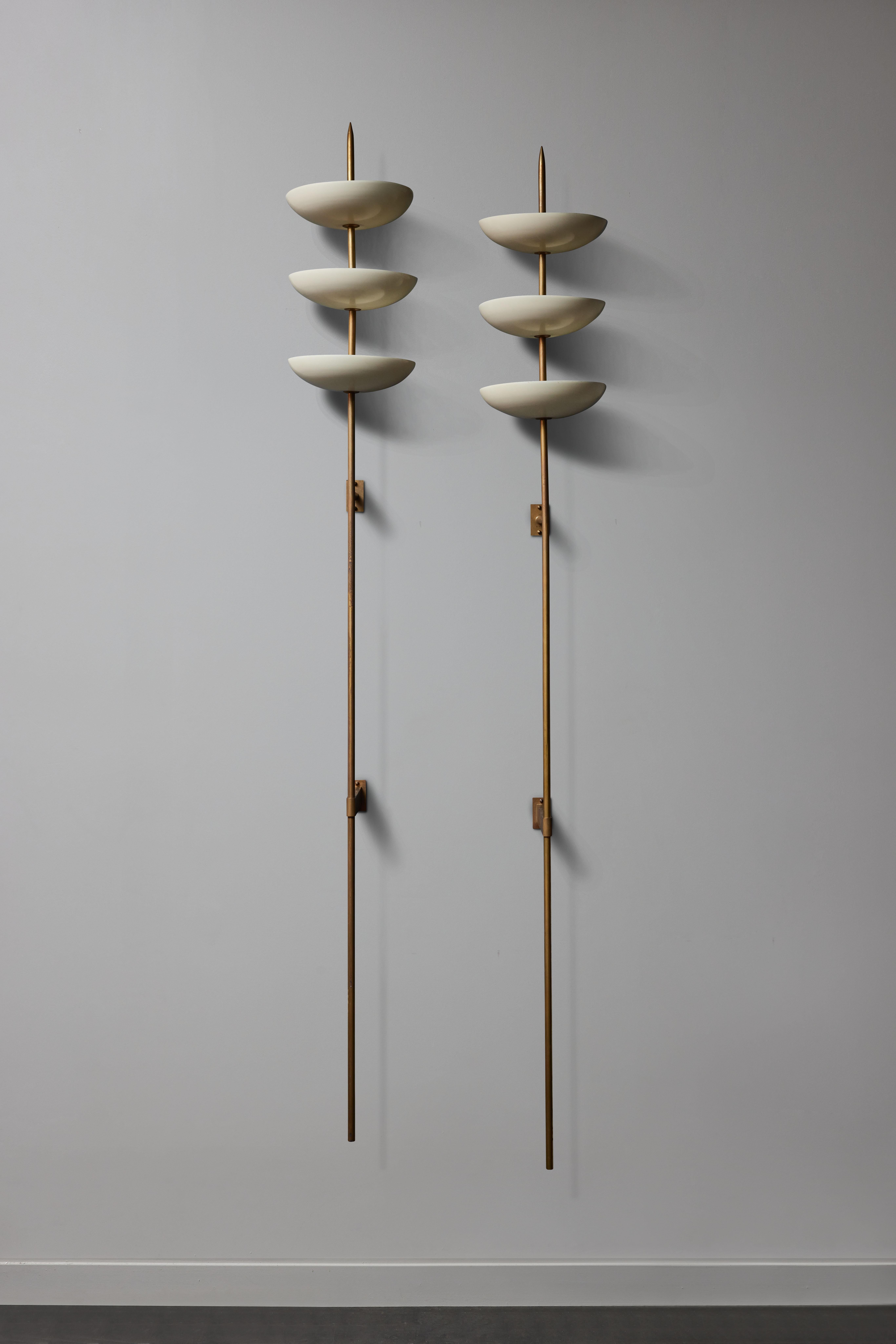 Pair of tall wall sconces made of two mounting brackets, long brass stem and three enameled metal shallow bowls each hosting two sources of light.