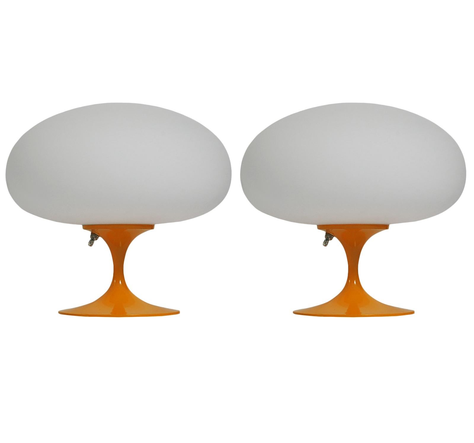 A gorgeous matching pair of tulip form table lamps after Laurel Lamp Company These feature an orange powder coated cast aluminum bases with mouth blown frosted white glass shades. The price includes the pair as shown.
